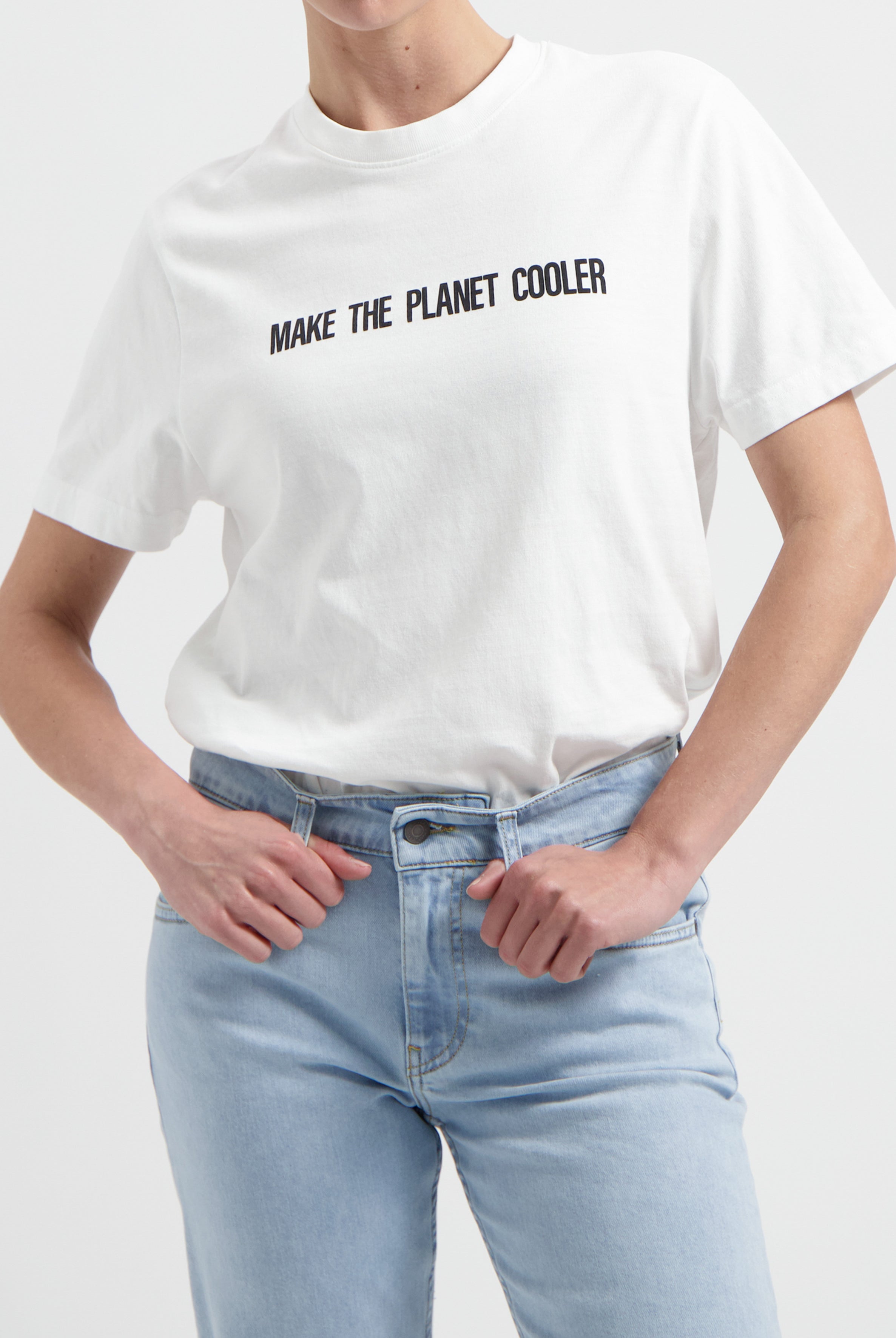 White eco-friendly T-shirt with "Make the Planet Cooler" slogan, paired with faded blue high-waisted jeans.