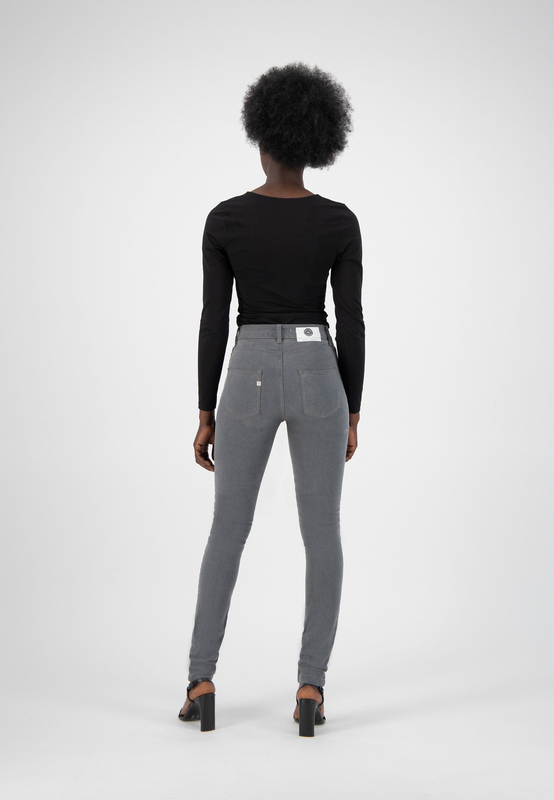 Black fitted long-sleeve top paired with high-waisted gray skinny jeans, showcasing a modern and sleek casual style.