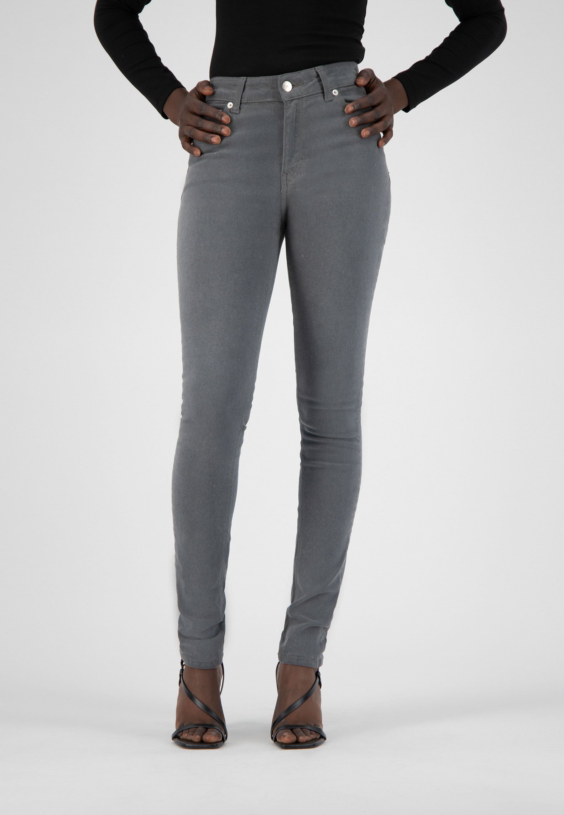 Gray high-waisted jeans paired with a black long-sleeve top and strappy black heels, showcasing a modern casual look.