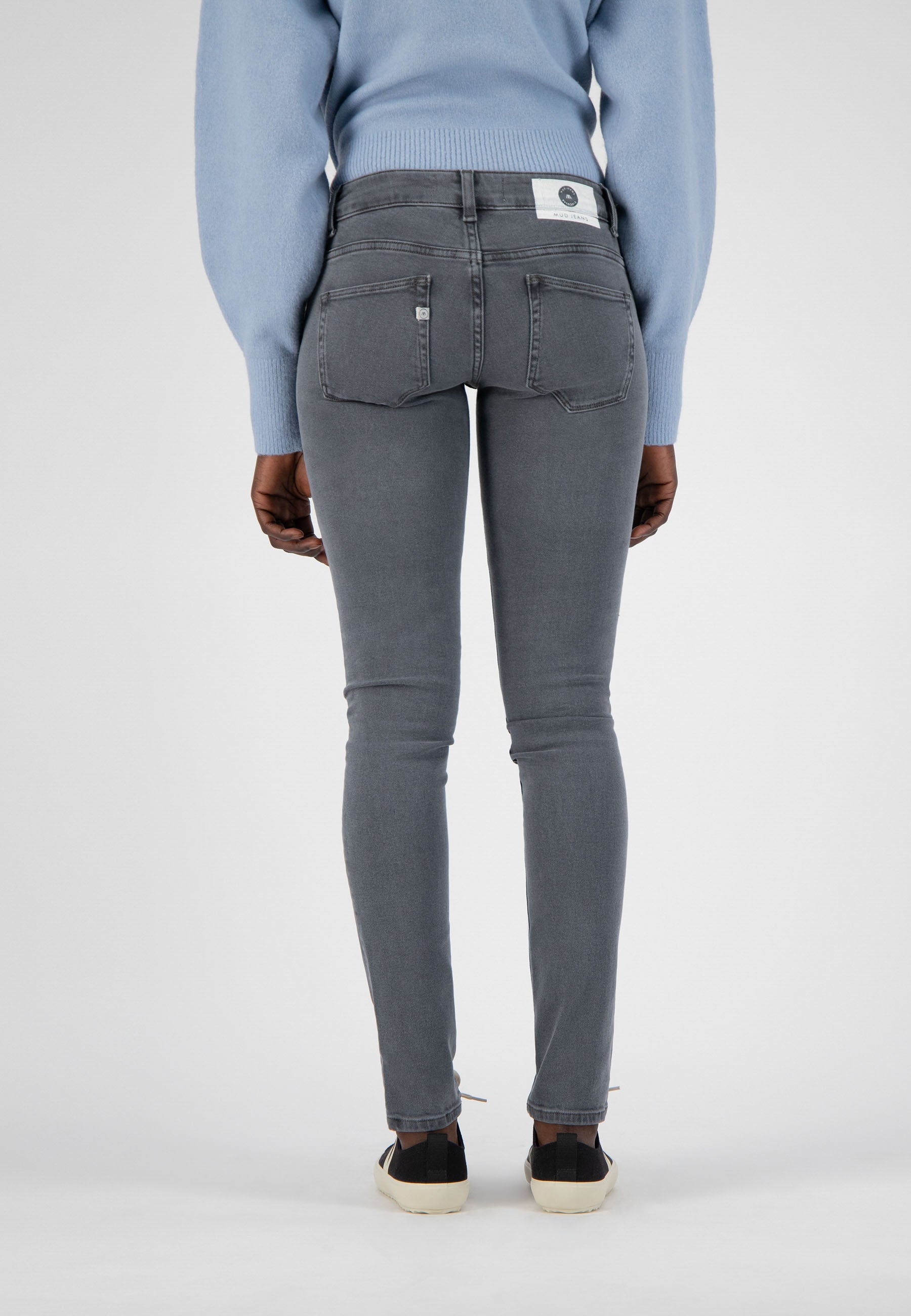 Gray slim-fit jeans made from organic cotton, worn with a light blue sweater, showcasing back pocket detail.