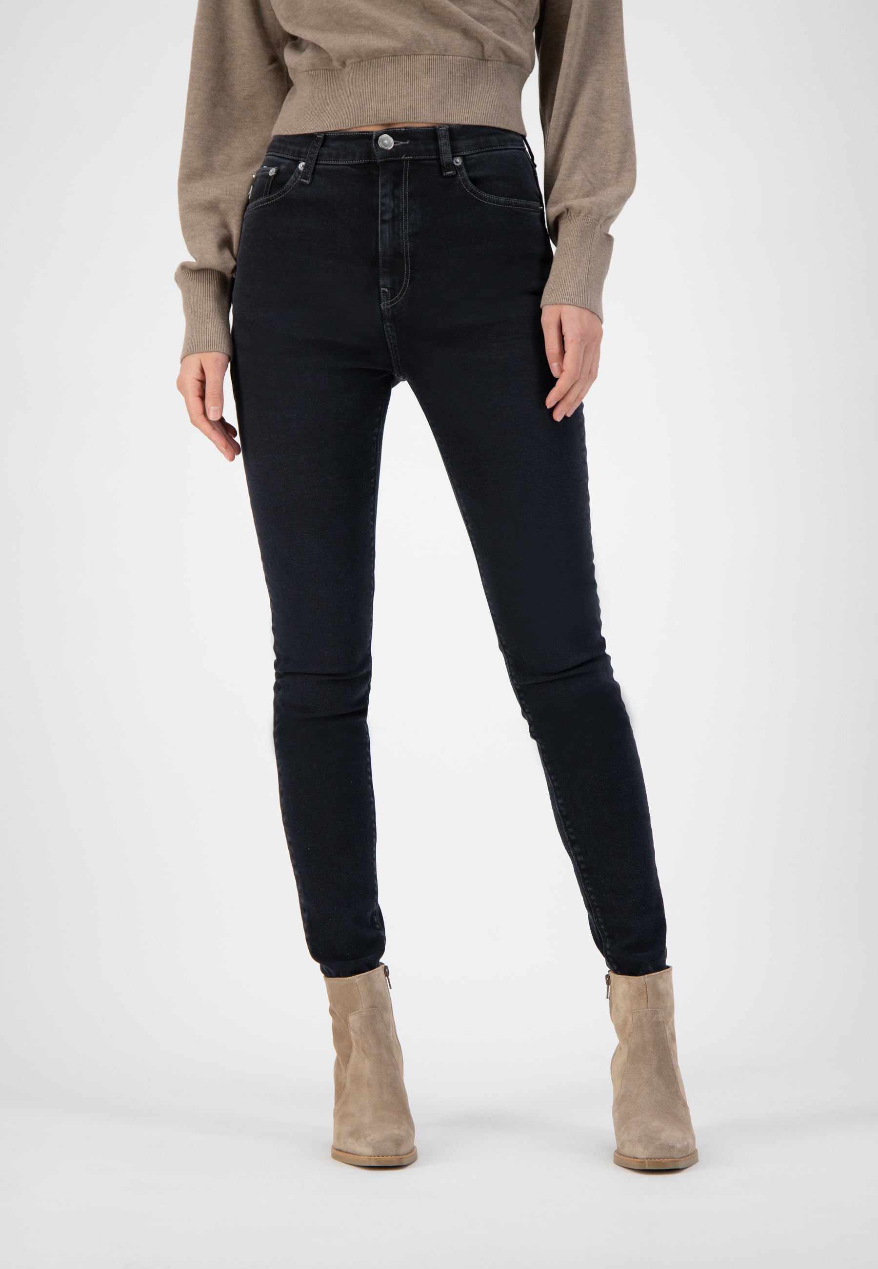 High-waisted black denim jeans paired with neutral beige ankle boots and a beige sweater, showcasing casual chic style.