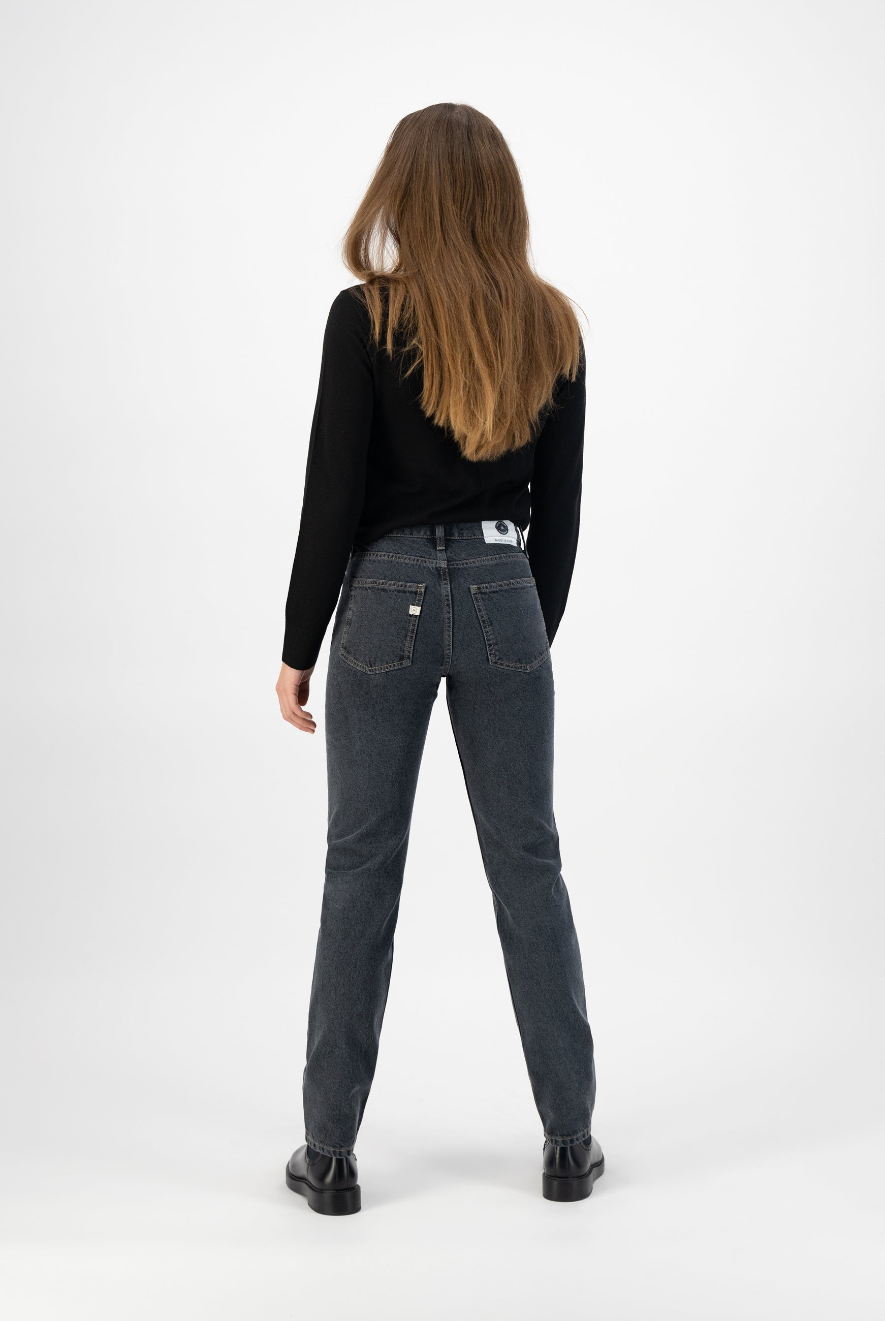 High-waisted dark gray denim jeans paired with a black long-sleeve sweater, showcasing a casual back view style.