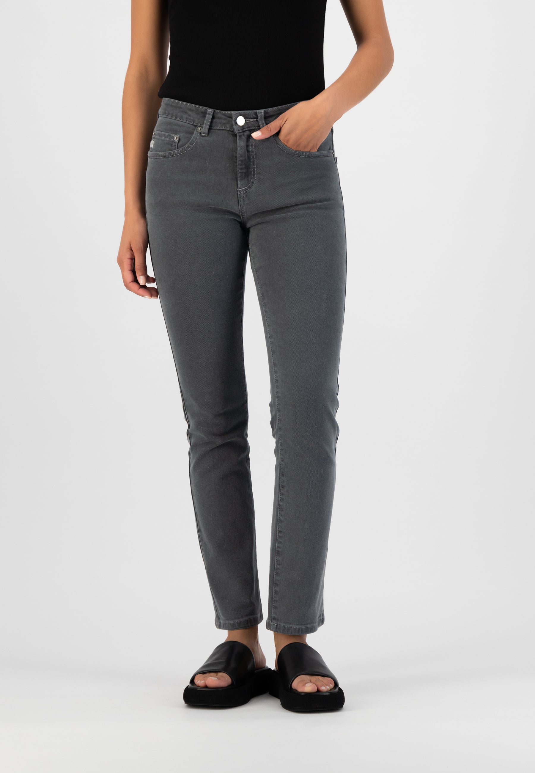 Gray slim-fit jeans paired with a black sleeveless top and black open-toe sandals, showcasing a modern casual outfit.