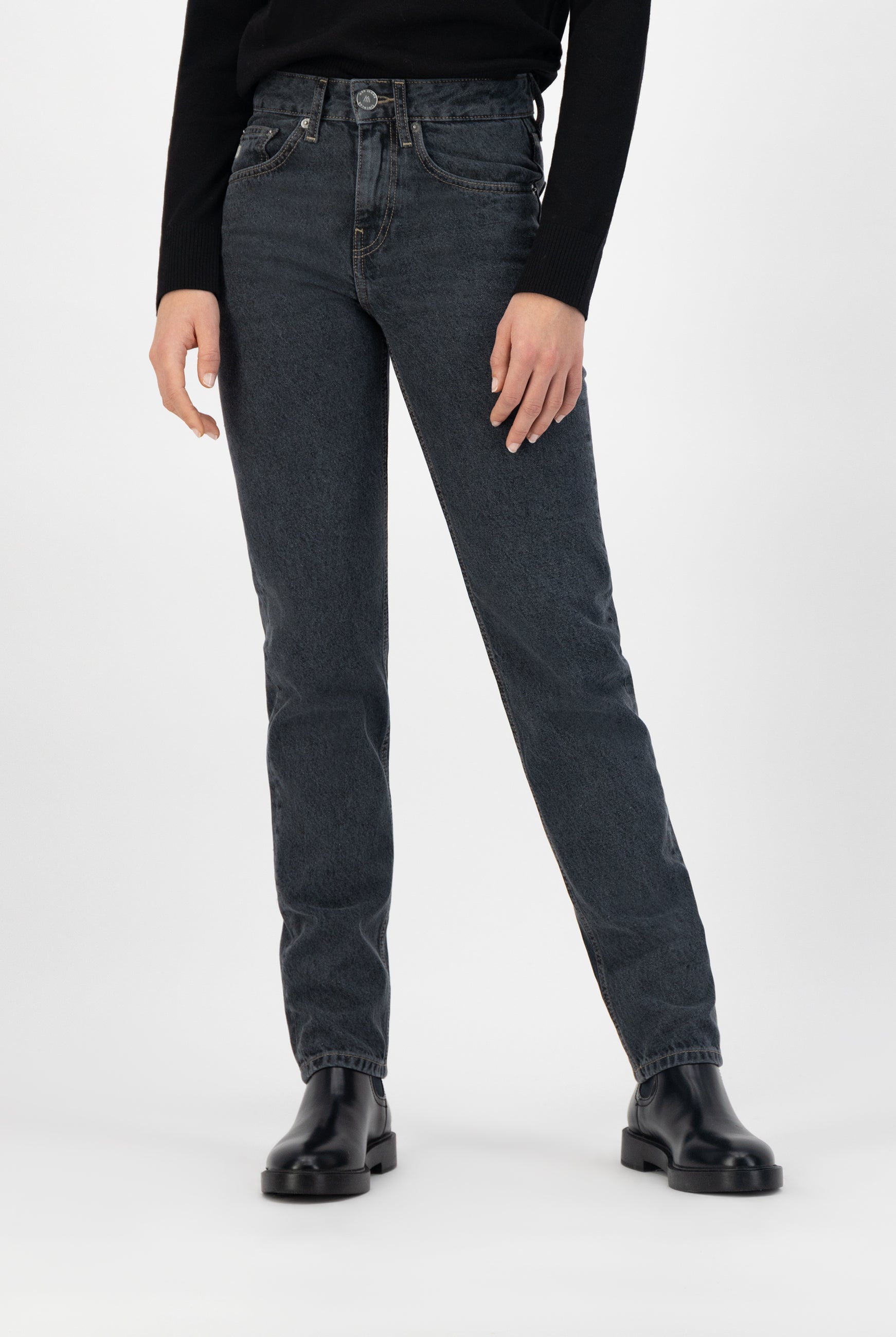 High-waisted, dark wash straight-leg jeans paired with a black long-sleeve top and black leather ankle boots.