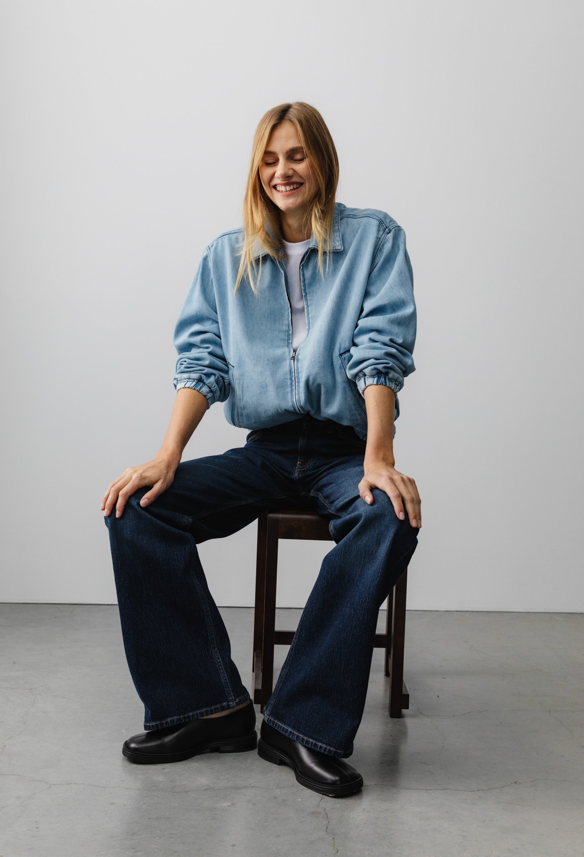 Casual outfit with light blue denim jacket and dark blue wide-leg jeans, worn with black shoes, sitting indoors.