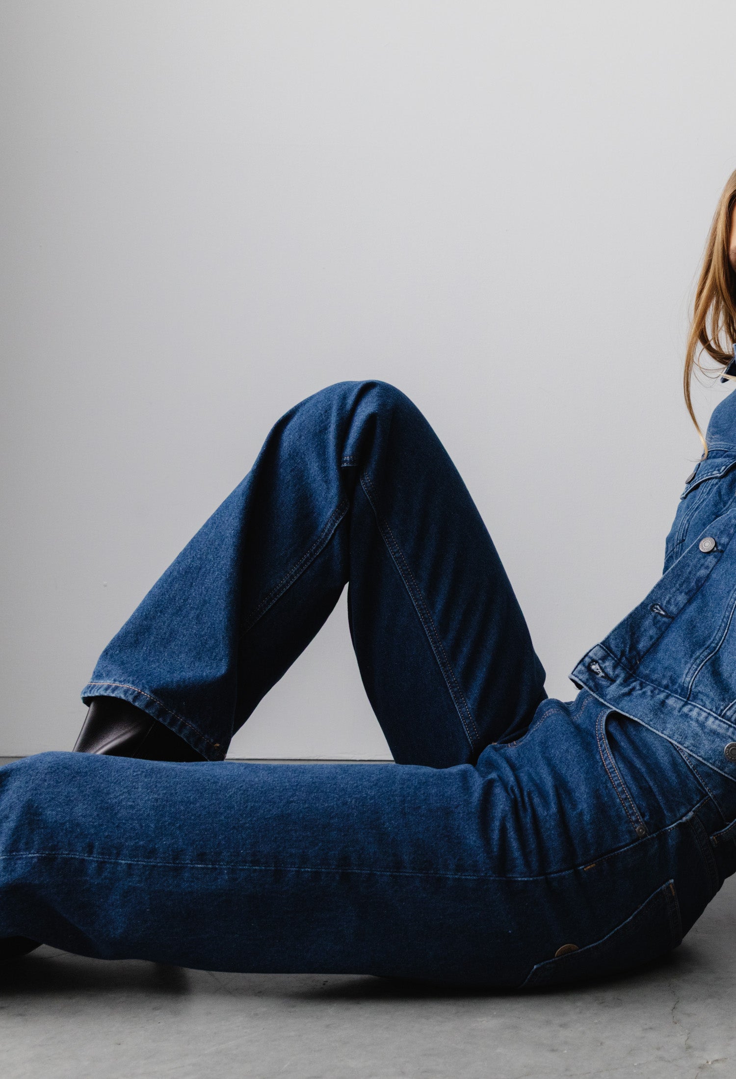 Casual blue denim ensemble featuring a relaxed-fit jacket and classic jeans, styled with a modern touch on a minimalist backdrop.