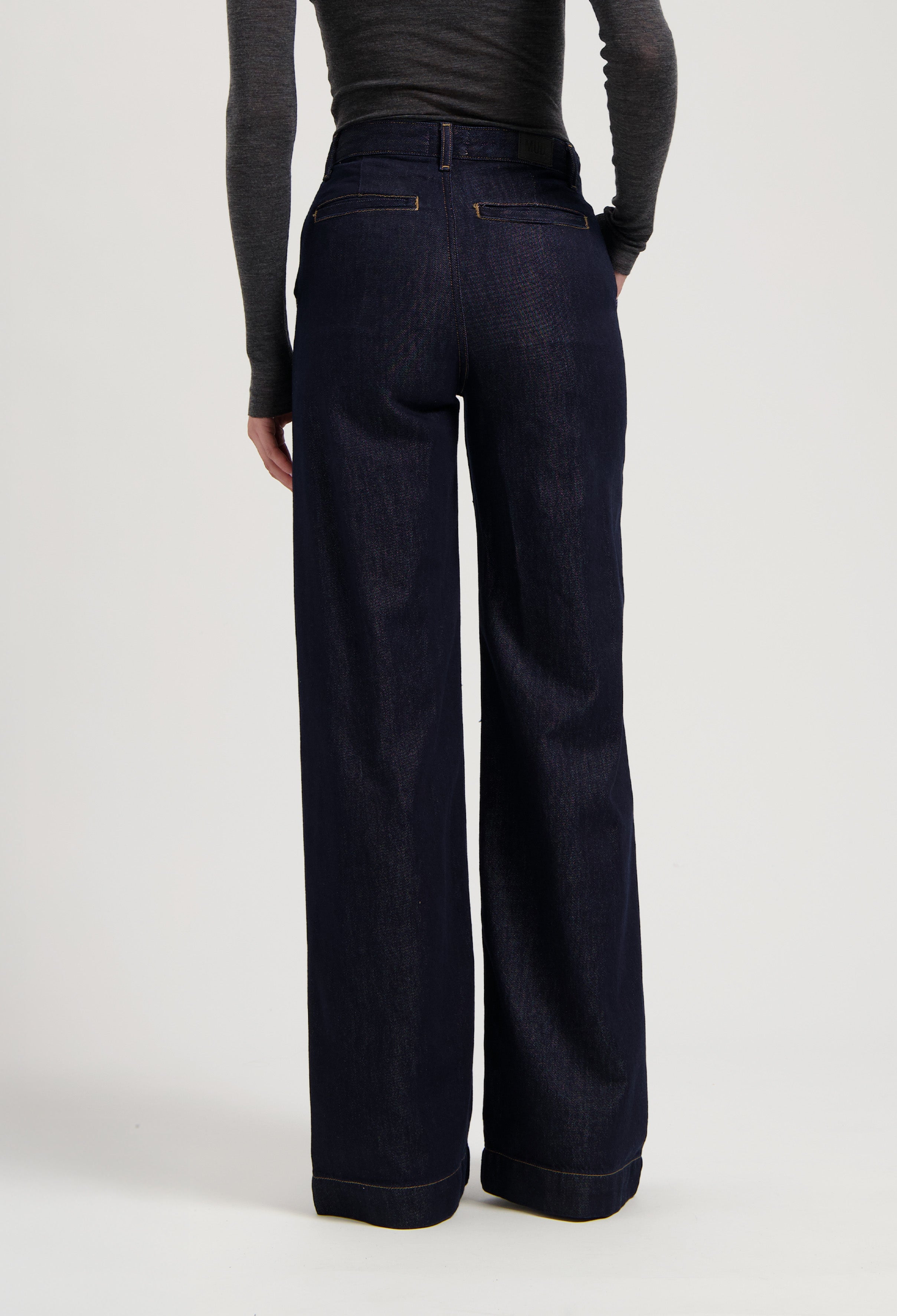 Dark blue, wide-leg jeans made from organic cotton, paired with a fitted long-sleeve, charcoal gray top.