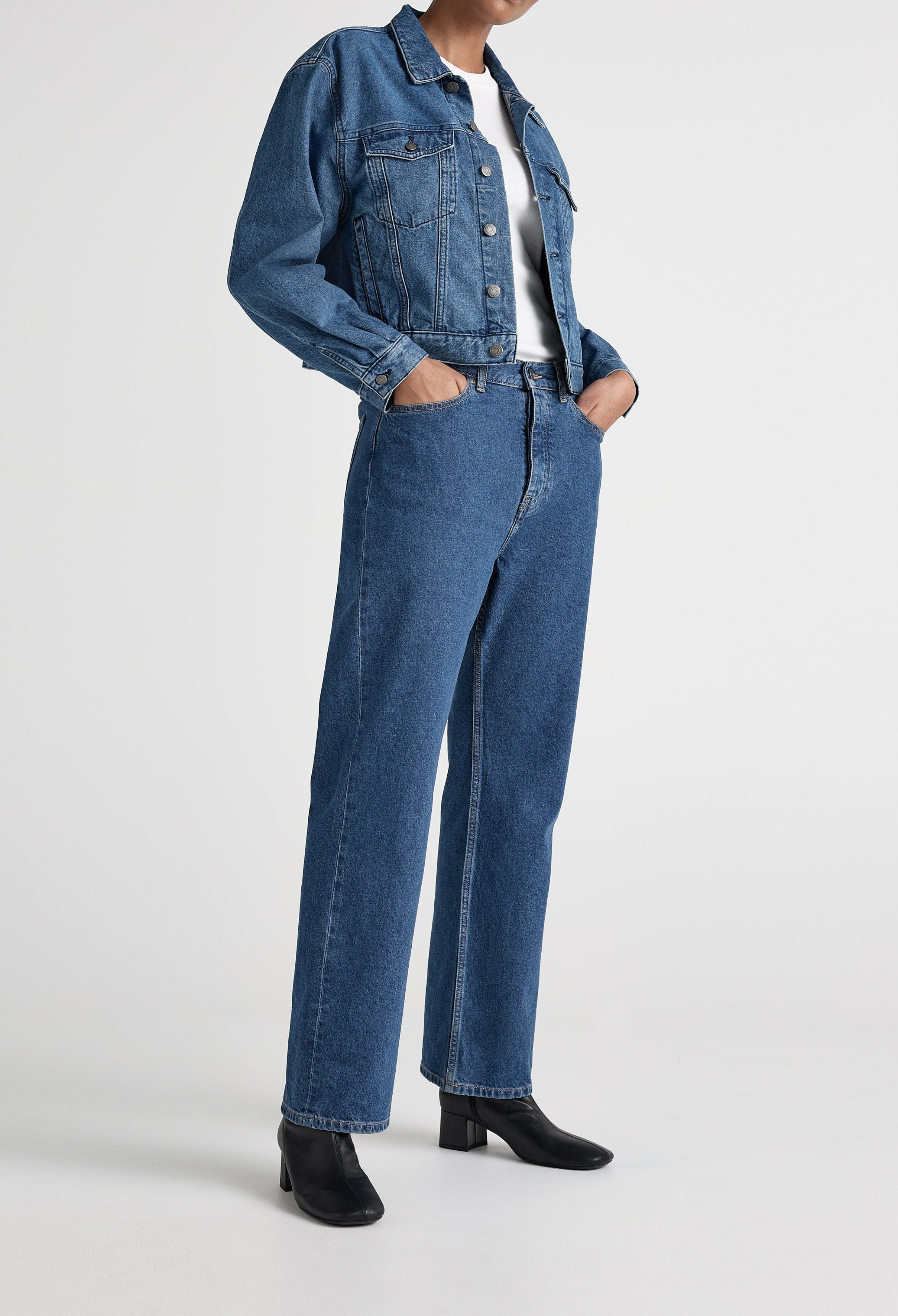 Blue denim jacket and high-waisted jeans ensemble with a white T-shirt, styled with black ankle boots on a white background.