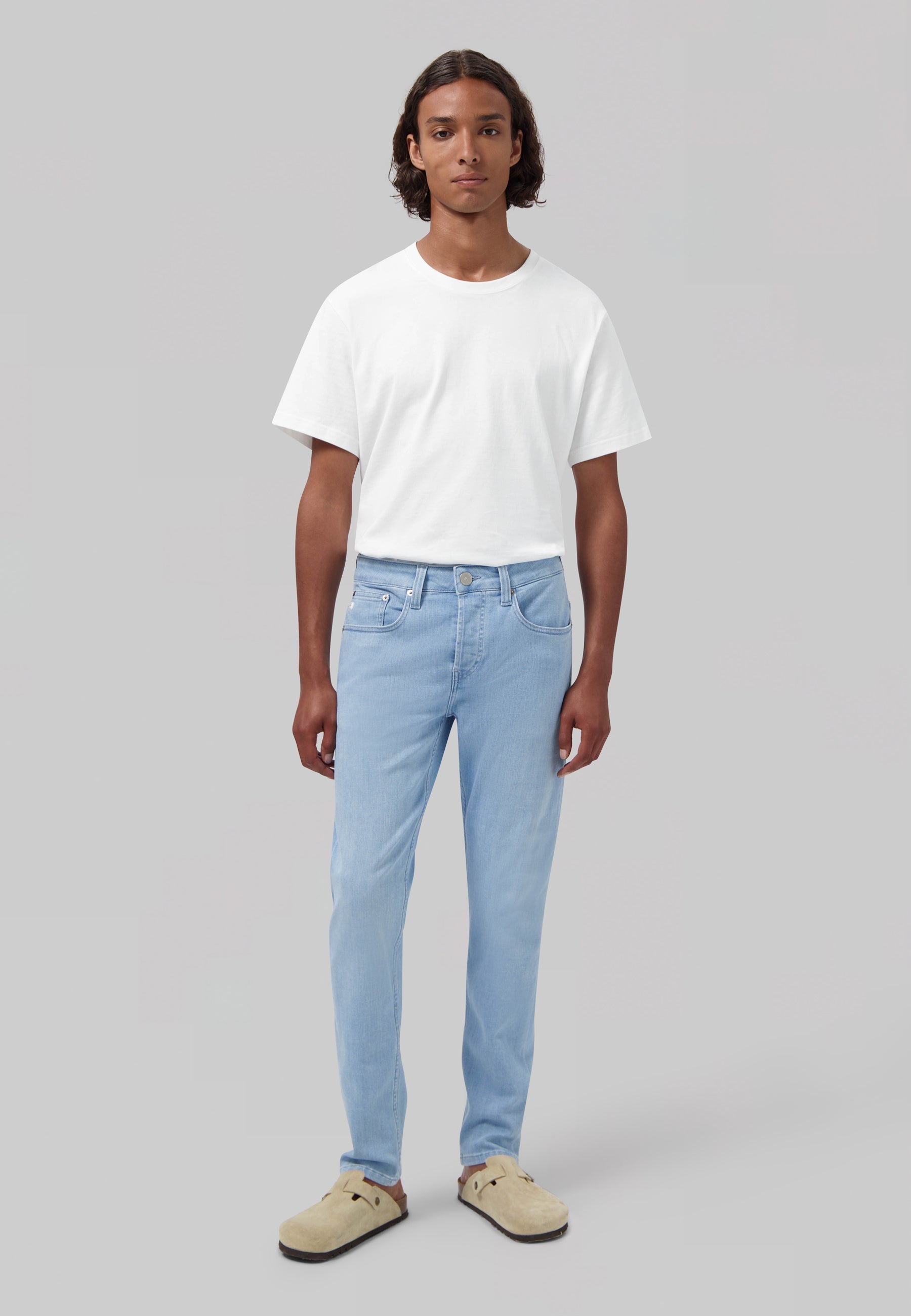 Sustainable MUD Jeans in classic blue denim, worn with a white shirt and navy sweater, showcasing ethical fashion.