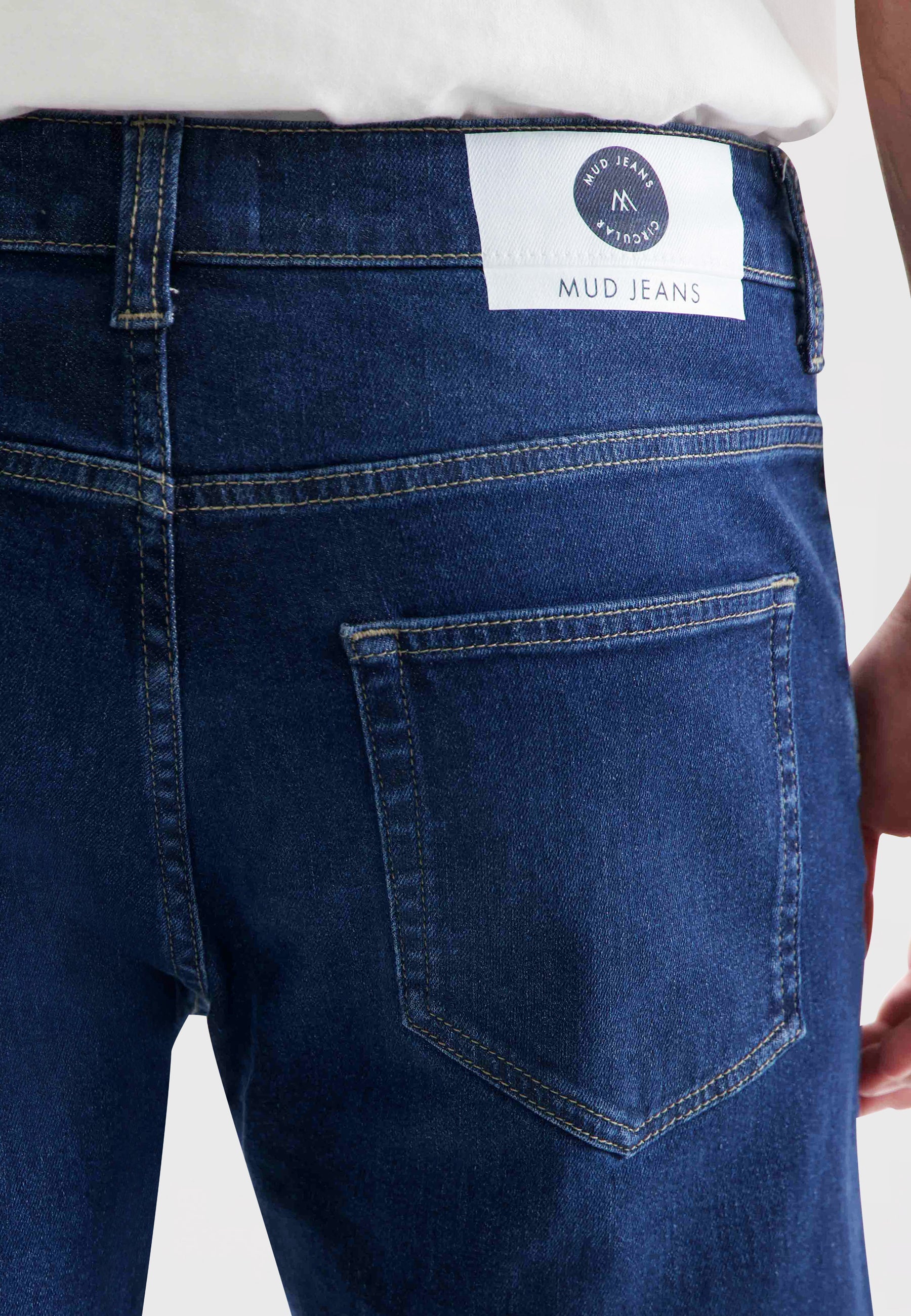 Sustainable MUD Jeans sleeveless jacket in dark blue denim, paired with a matching blue cap, showcasing eco-friendly fashion.