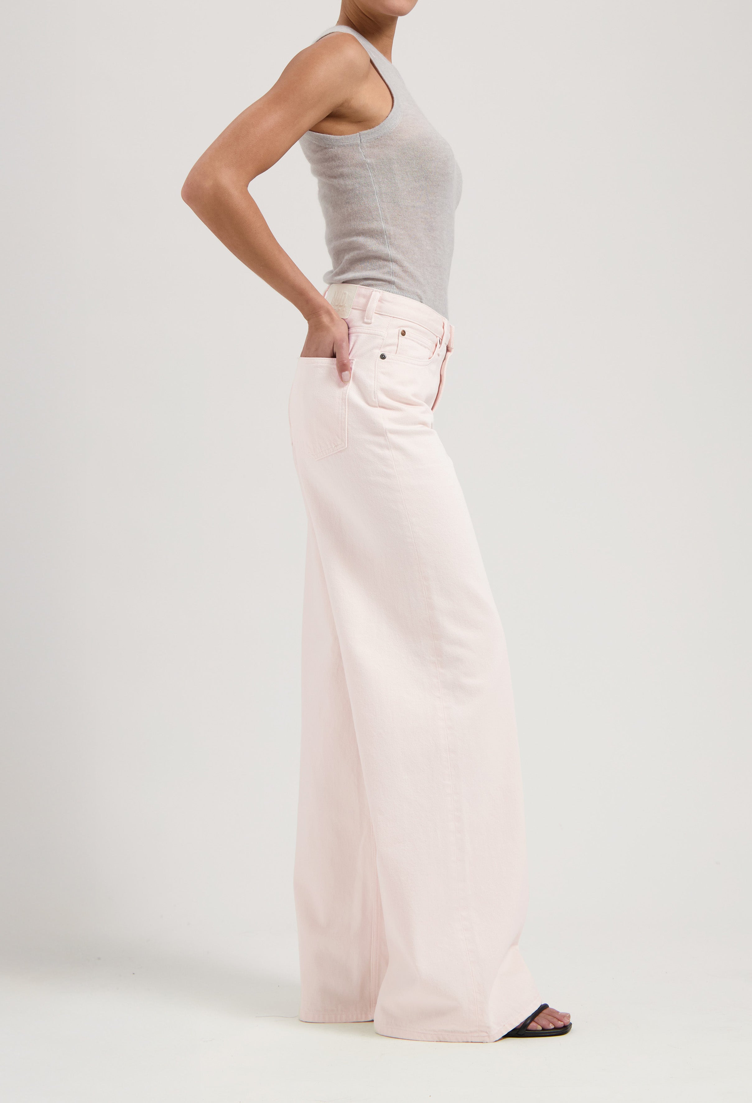Wide-leg light pink jeans paired with a fitted gray tank top, showcasing a minimalist and modern fashion look.