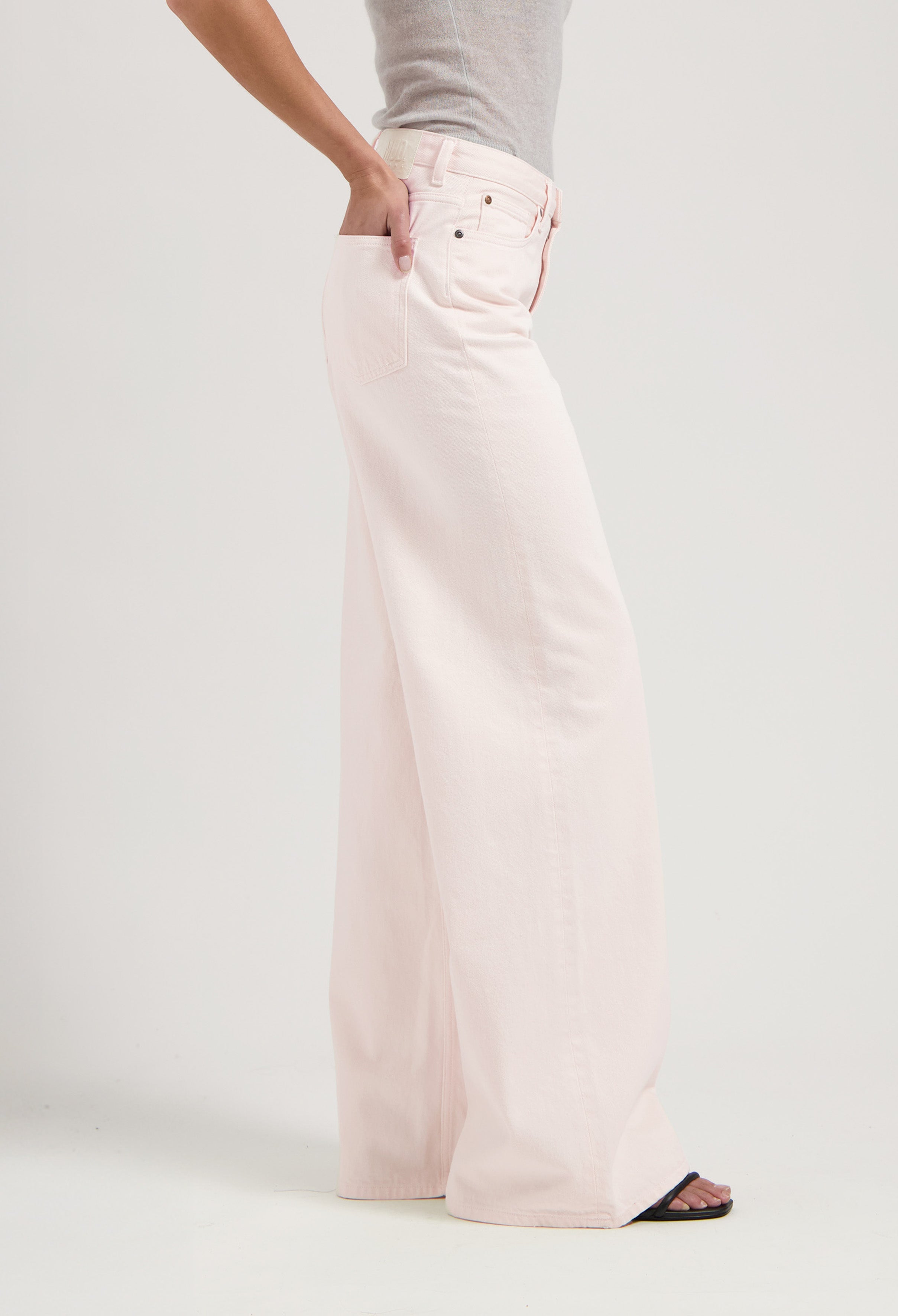 Wide-leg pants in soft pastel pink denim, worn with a fitted gray top, showcasing casual chic style with side pocket detail.