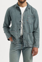 Sustainable MUD Jeans featuring light blue denim, emphasizing ethical fashion, paired with a gray T-shirt.