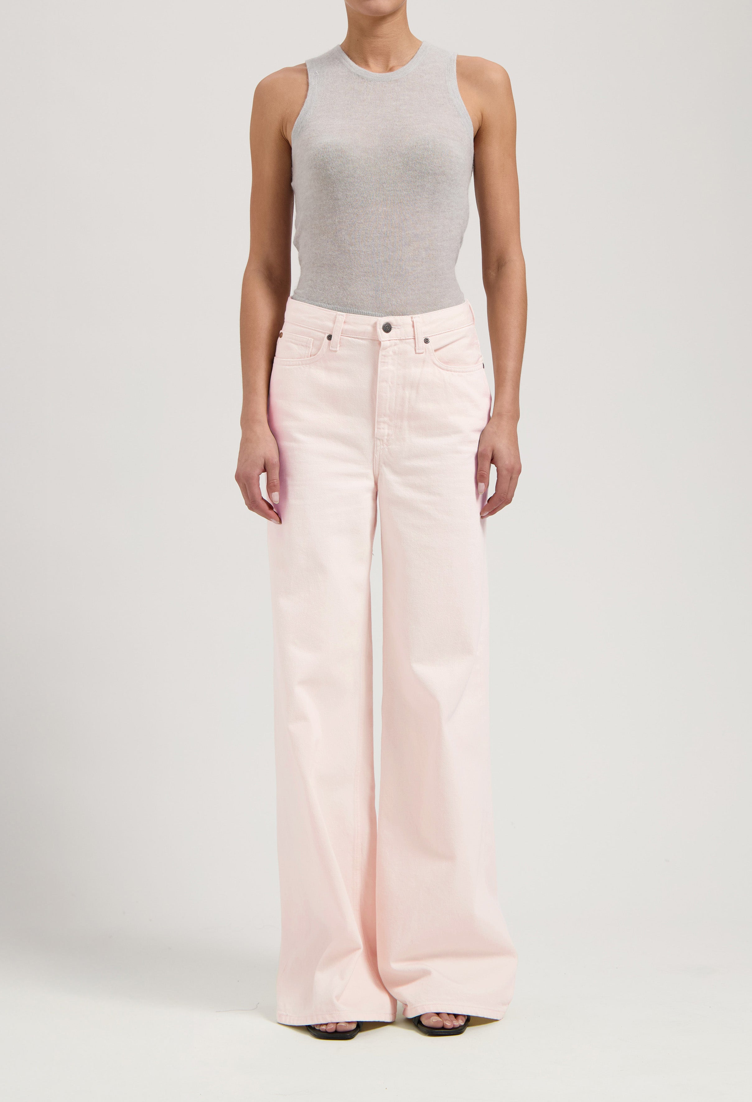 Wide-leg pale pink jeans paired with a form-fitting light gray sleeveless top, showcasing casual chic style.