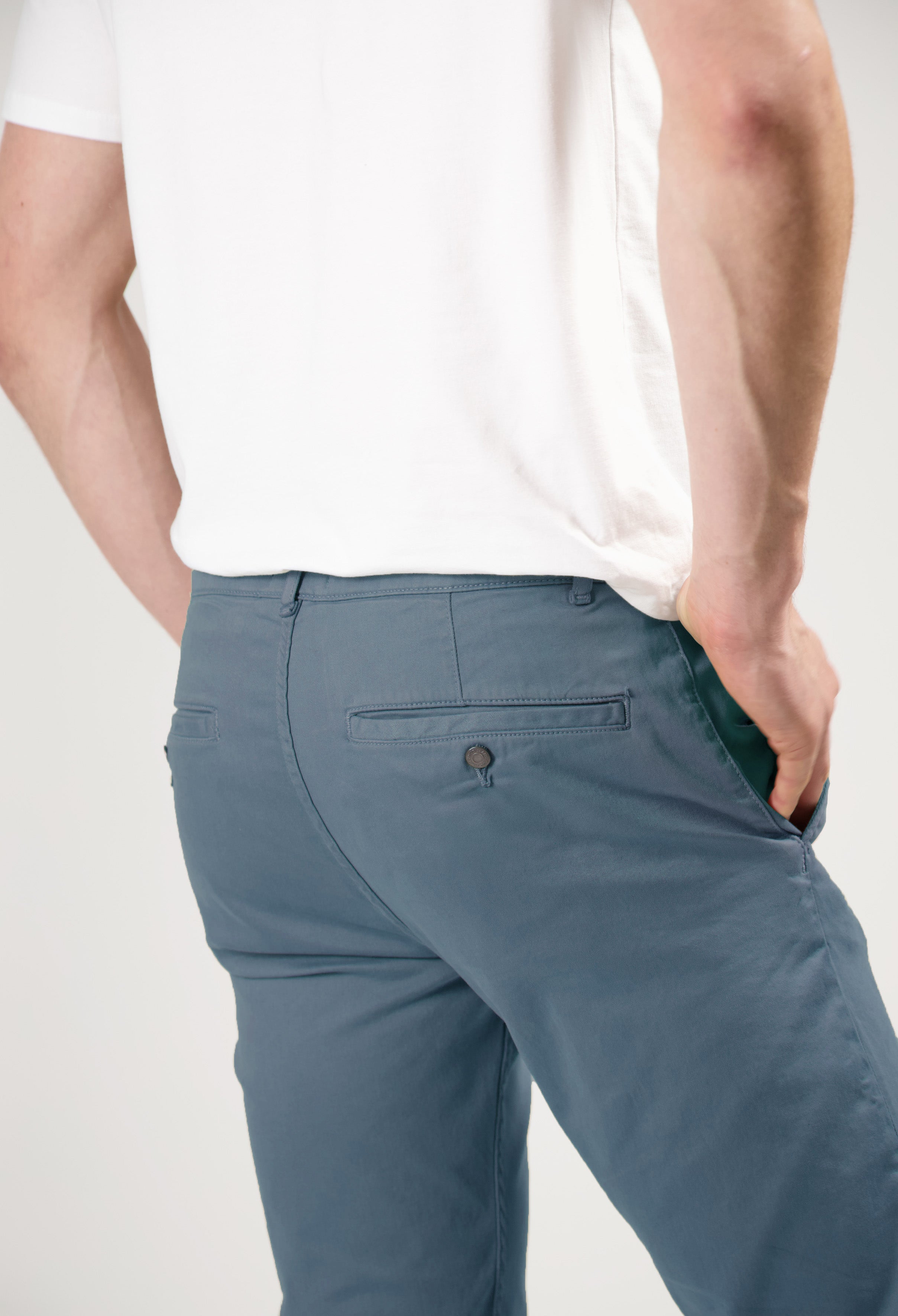 Sustainable MUD Jeans in light blue organic cotton, slim fit, paired with a gray T-shirt and white sneakers, side view.