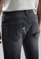 Sustainable MUD Jeans in light blue denim, crafted ethically from organic cotton, shown from the back with a white tee.