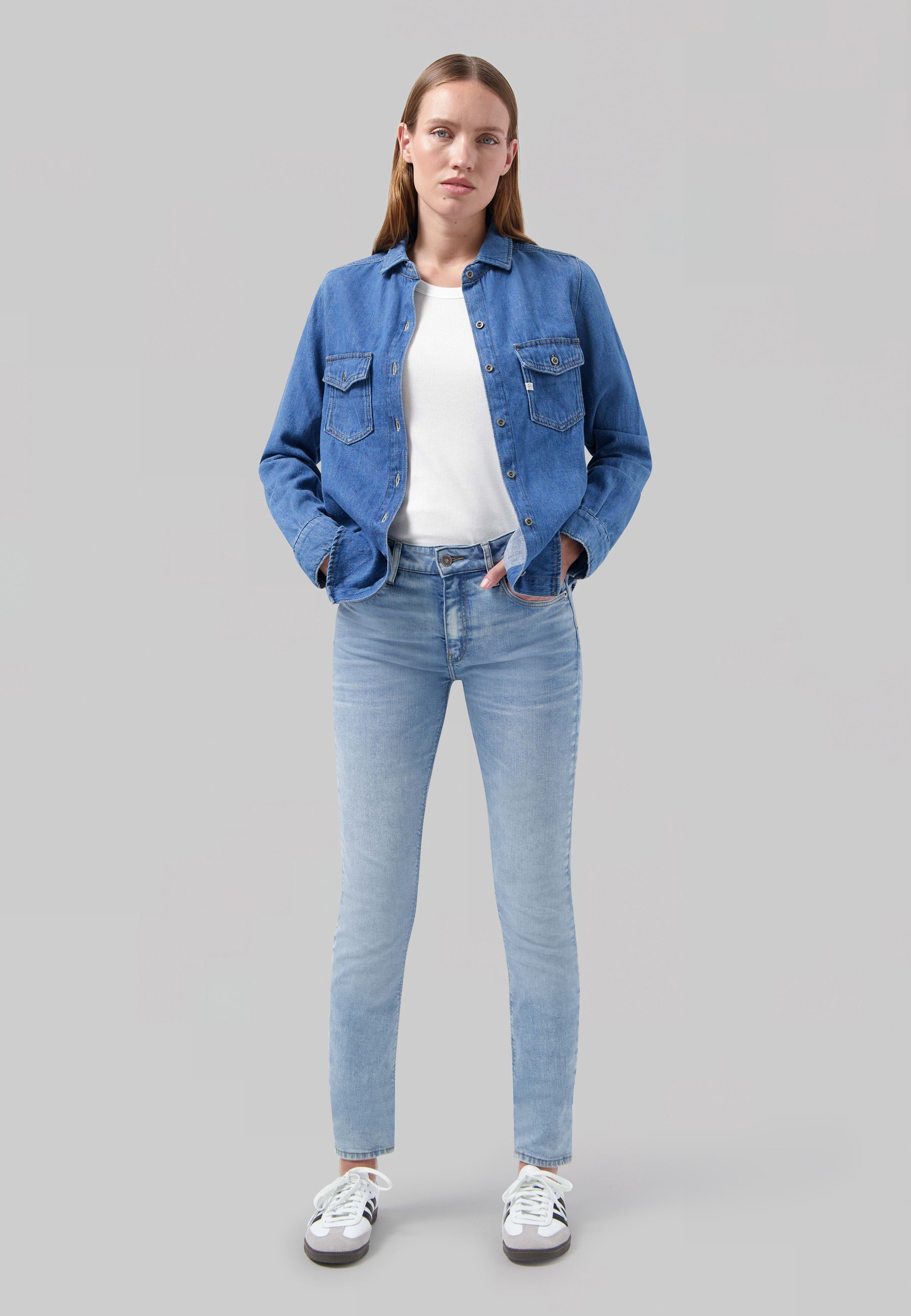 Woman in light blue denim outfit with white top, showing a casual style.