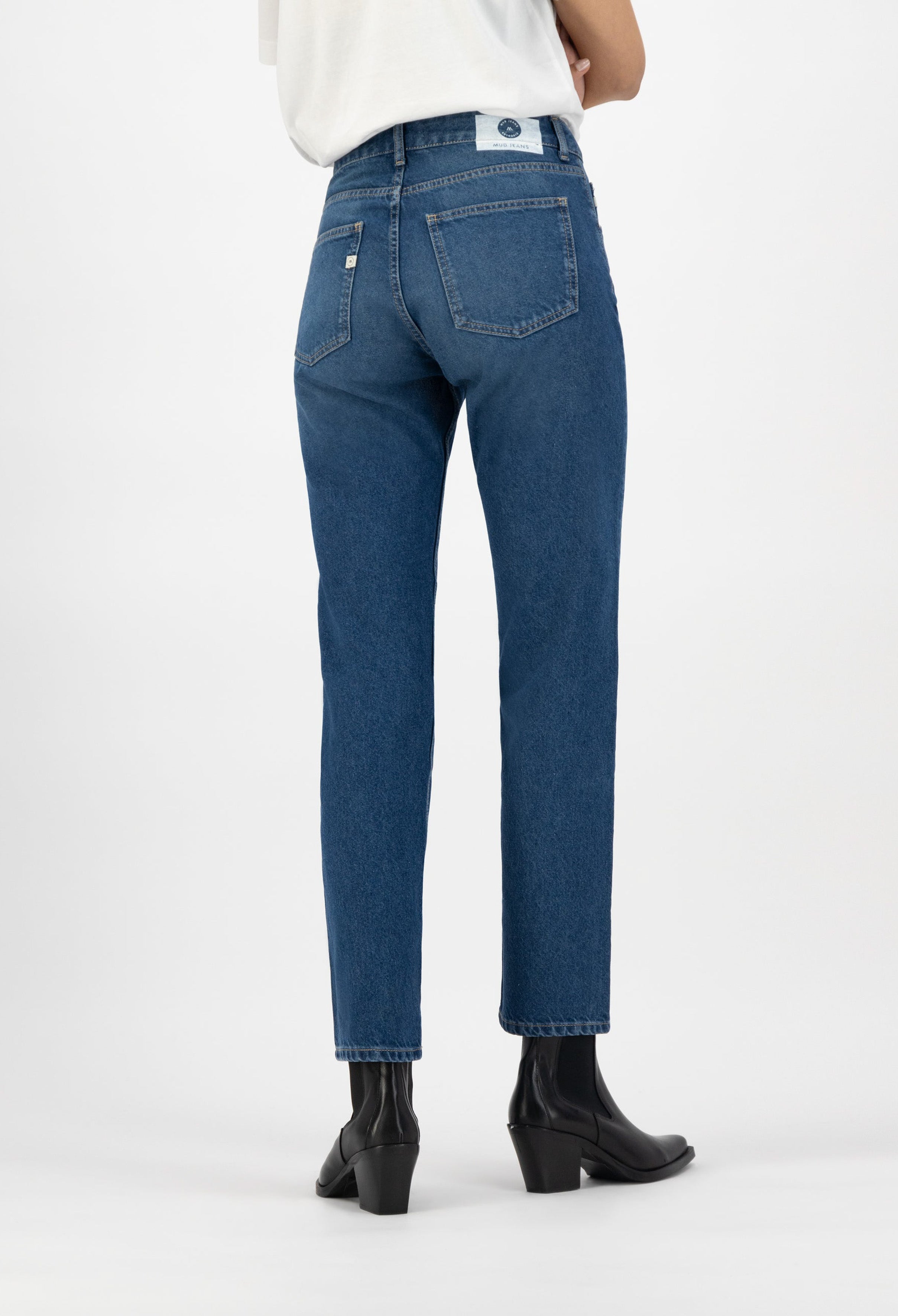 High-waist blue jeans made from organic cotton, featuring a straight-leg cut, worn with black ankle boots on white background.