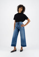 Casual fashion outfit featuring high-waisted, wide-leg blue denim jeans and a classic black t-shirt, perfect for everyday wear.