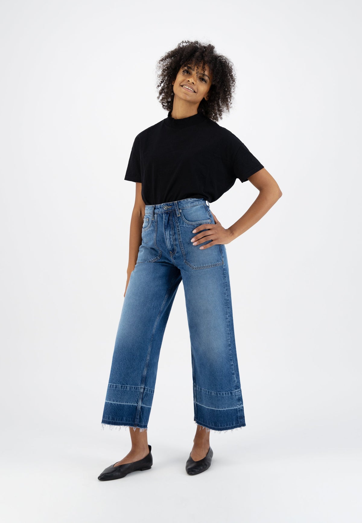 Casual fashion outfit featuring high-waisted, wide-leg blue denim jeans and a classic black t-shirt, perfect for everyday wear.