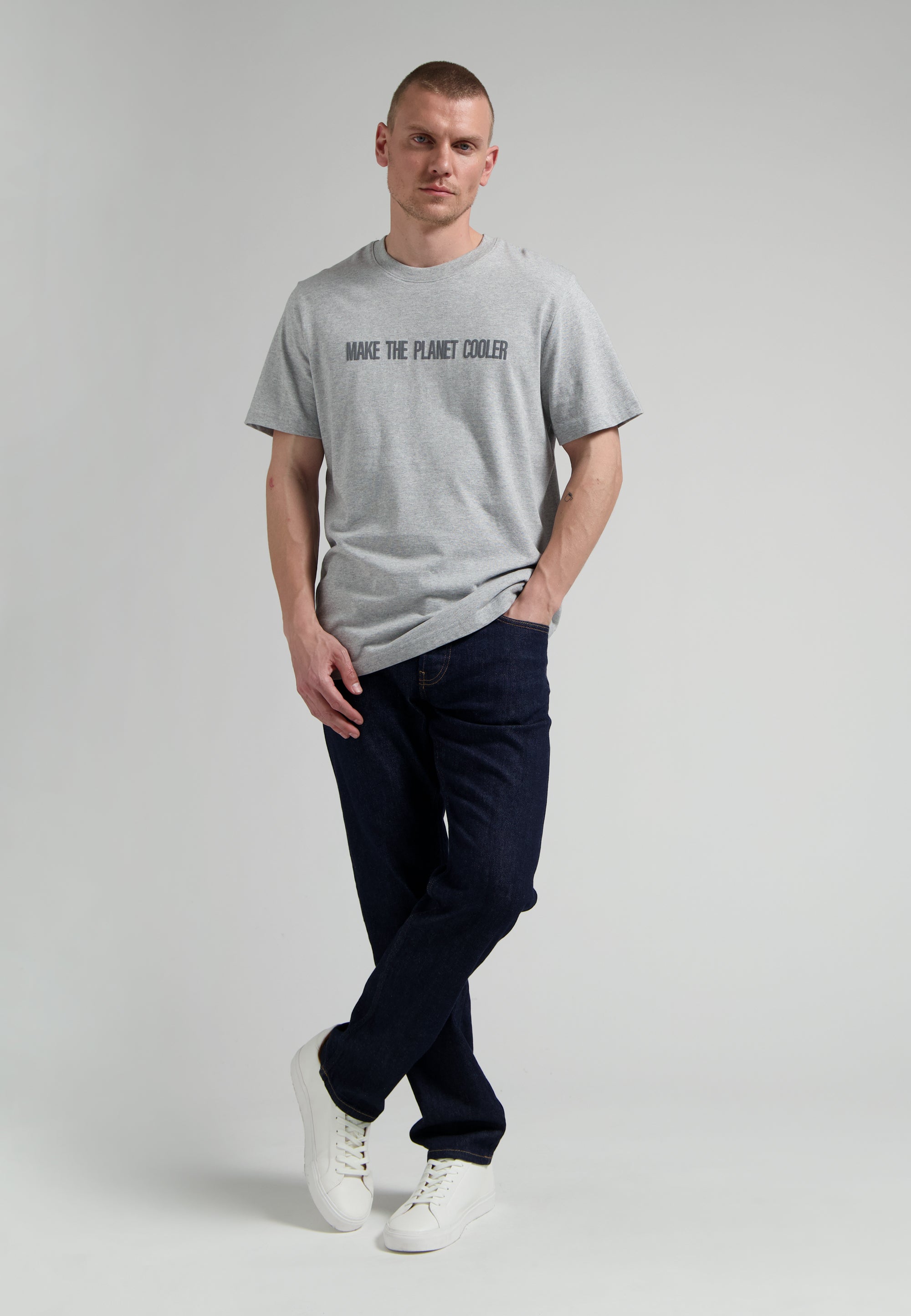 Sustainable MUD Jeans in classic blue denim, crafted from ethical materials, paired with a simple black tee and white sneakers.