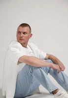 Sustainable MUD Jeans in deep blue denim, crafted ethically from organic cotton, paired with a casual white T-shirt.