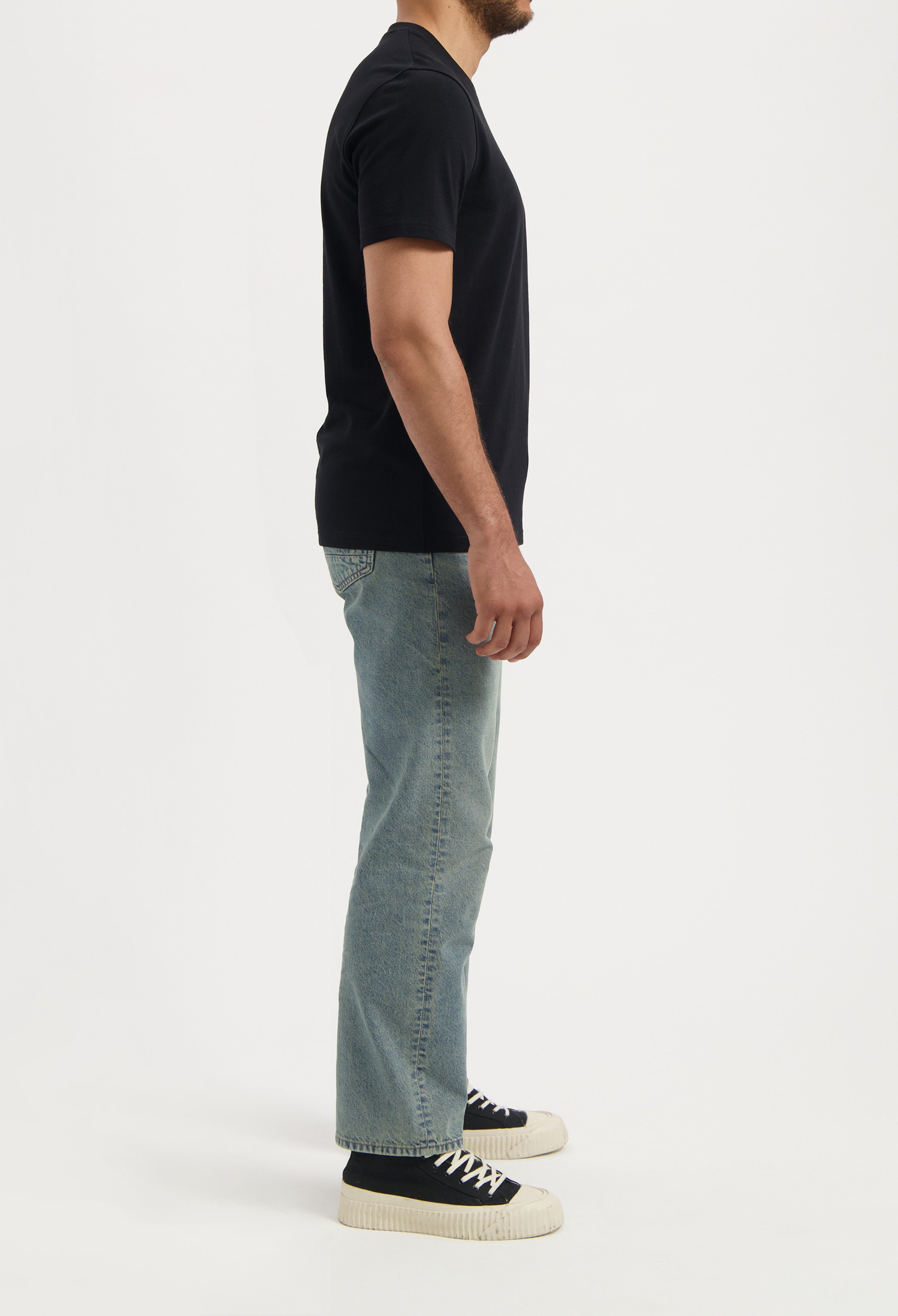 Sustainable MUD Jeans in dark blue denim, styled with a matching jacket and white sneakers, emphasizing ethical fashion.