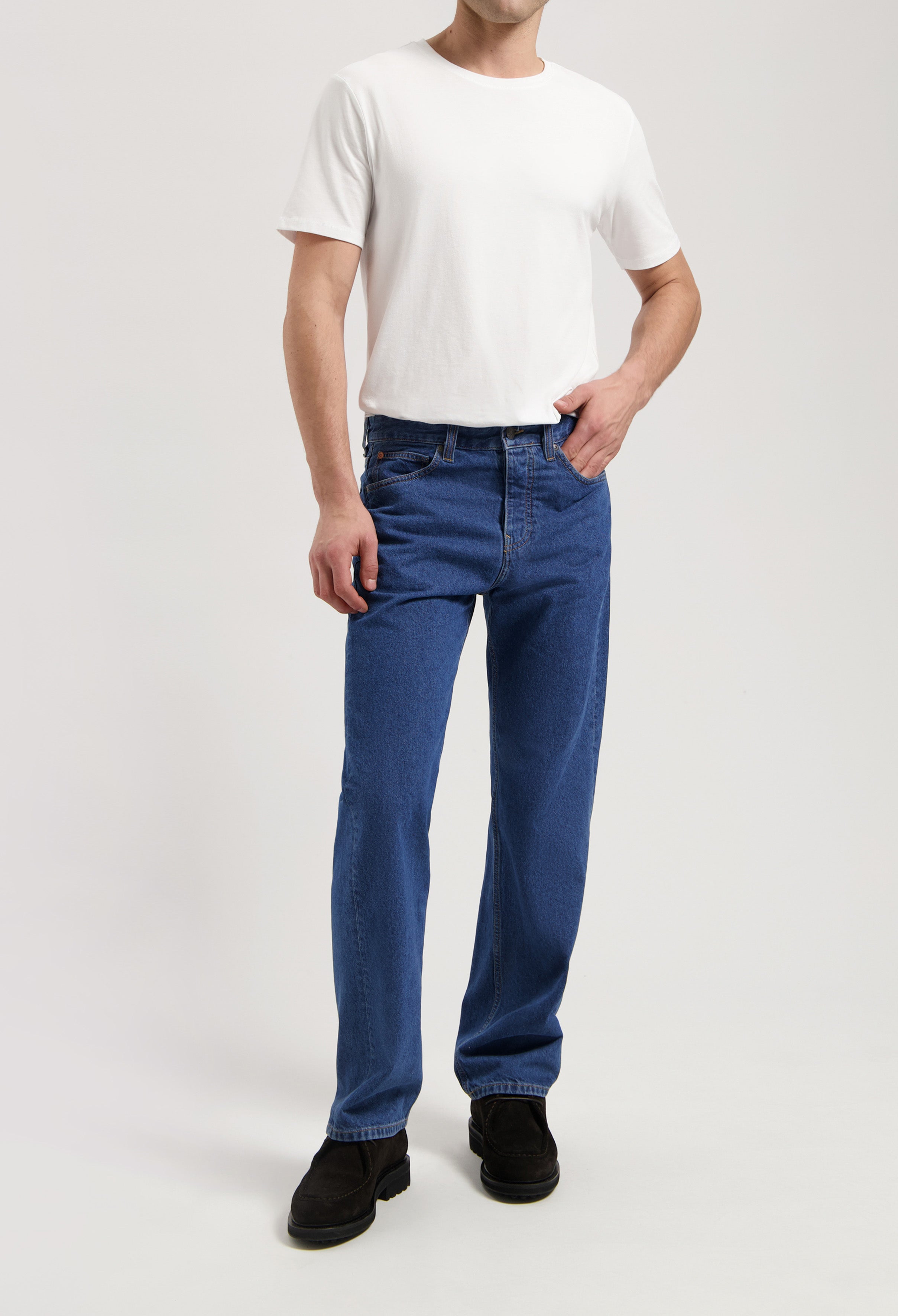 Sustainable MUD Jeans in dark gray denim, slim fit, showcasing ethical fashion paired with black leather shoes.