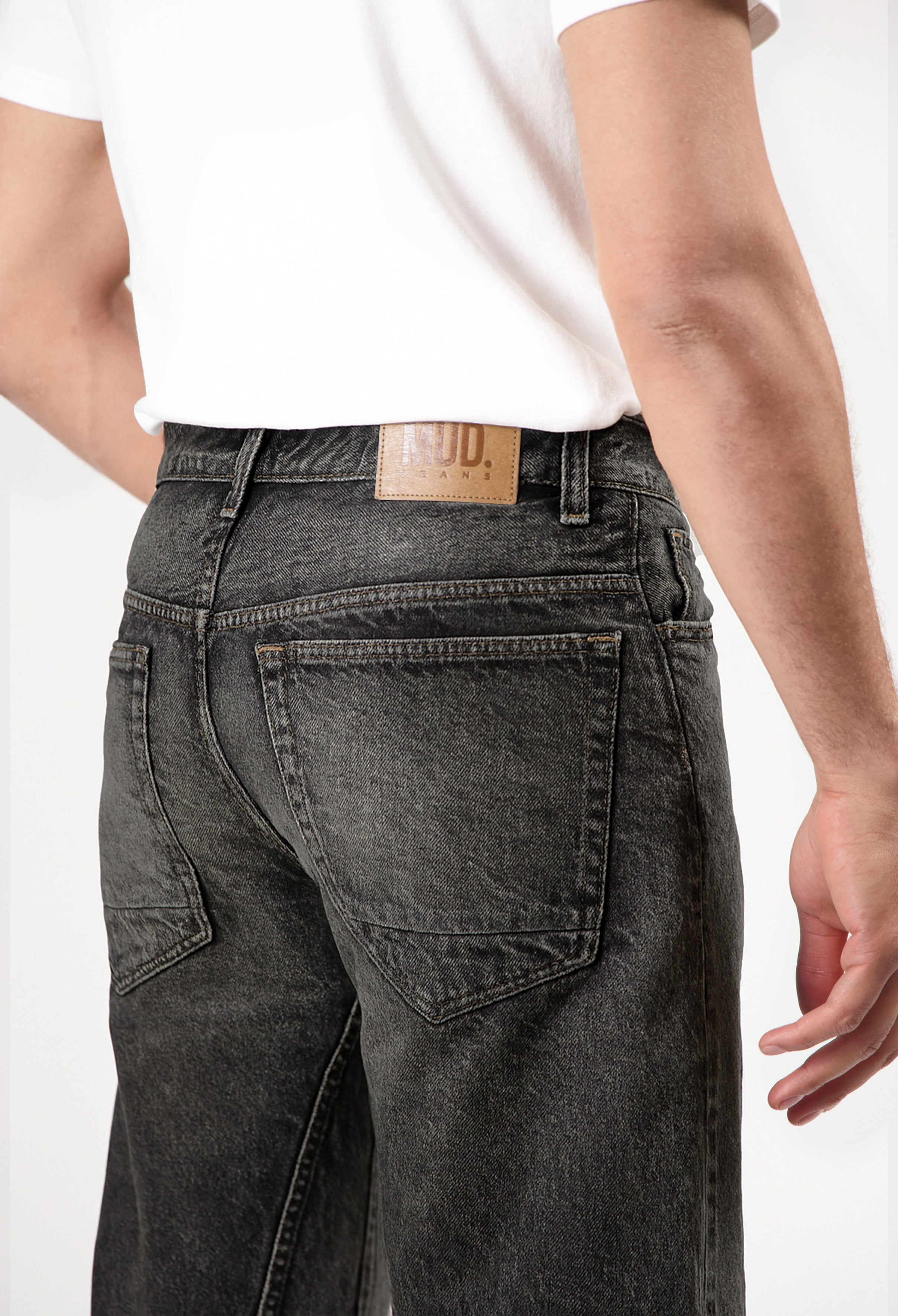 Sustainable MUD Jeans in dark blue denim, featuring back pocket detail and ethical craftsmanship, paired with a white top.