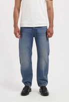 Sustainable MUD Jeans crafted from organic cotton in a light blue shade, paired with a black t-shirt, highlighting ethical fashion.