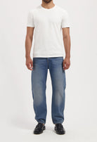 Sustainable MUD Jeans in light blue, crafted from ethical organic cotton, paired with white sneakers for a casual style.
