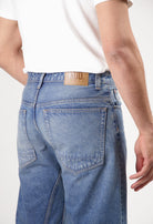 Sustainable MUD Jeans in light blue denim, ethical fashion, paired with black tee and black shoes for a classic look.