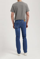 Sustainable Mud Jeans in beige, tailored fit crafted from organic cotton, paired with a simple gray t-shirt and casual sneakers.