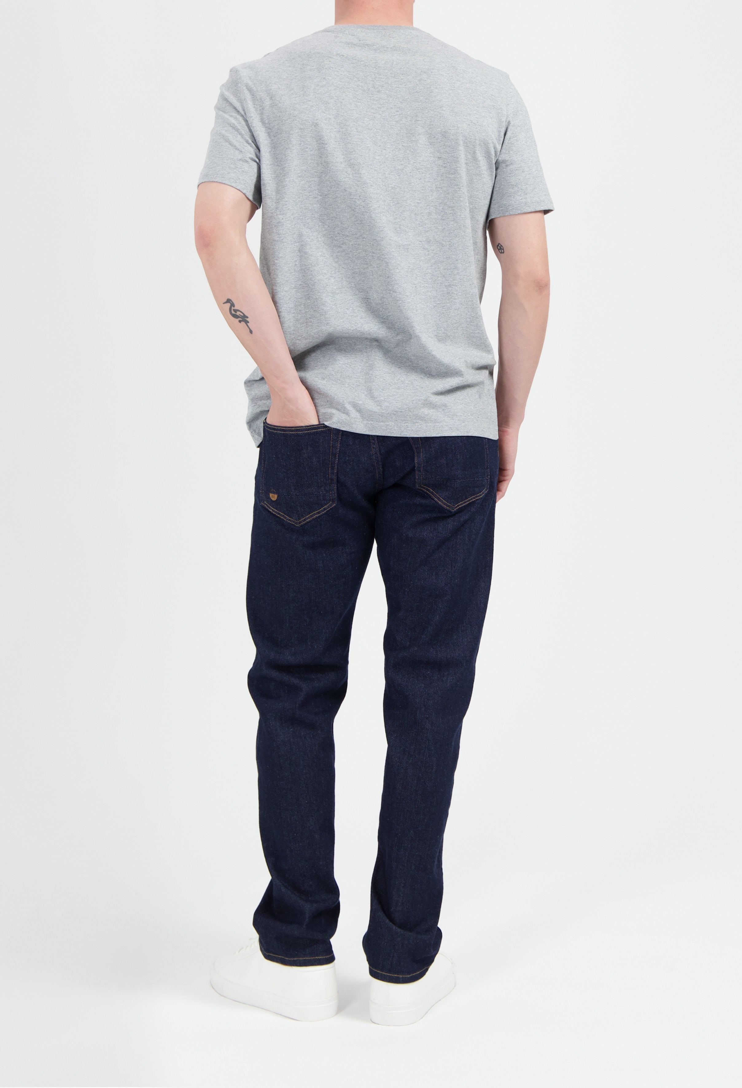 Sustainable MUD Jeans in deep blue denim, showcasing ethical fashion, paired with a casual gray T-shirt and white sneakers.