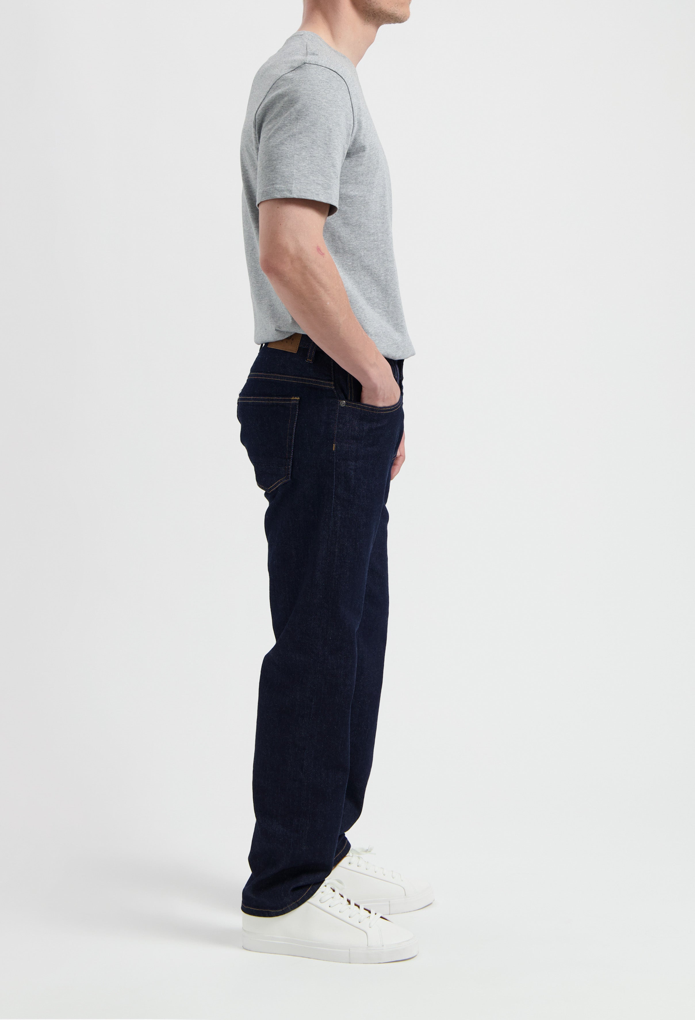 Sustainable MUD Jeans crafted from organic cotton in classic blue denim, paired with a gray t-shirt and white sneakers.