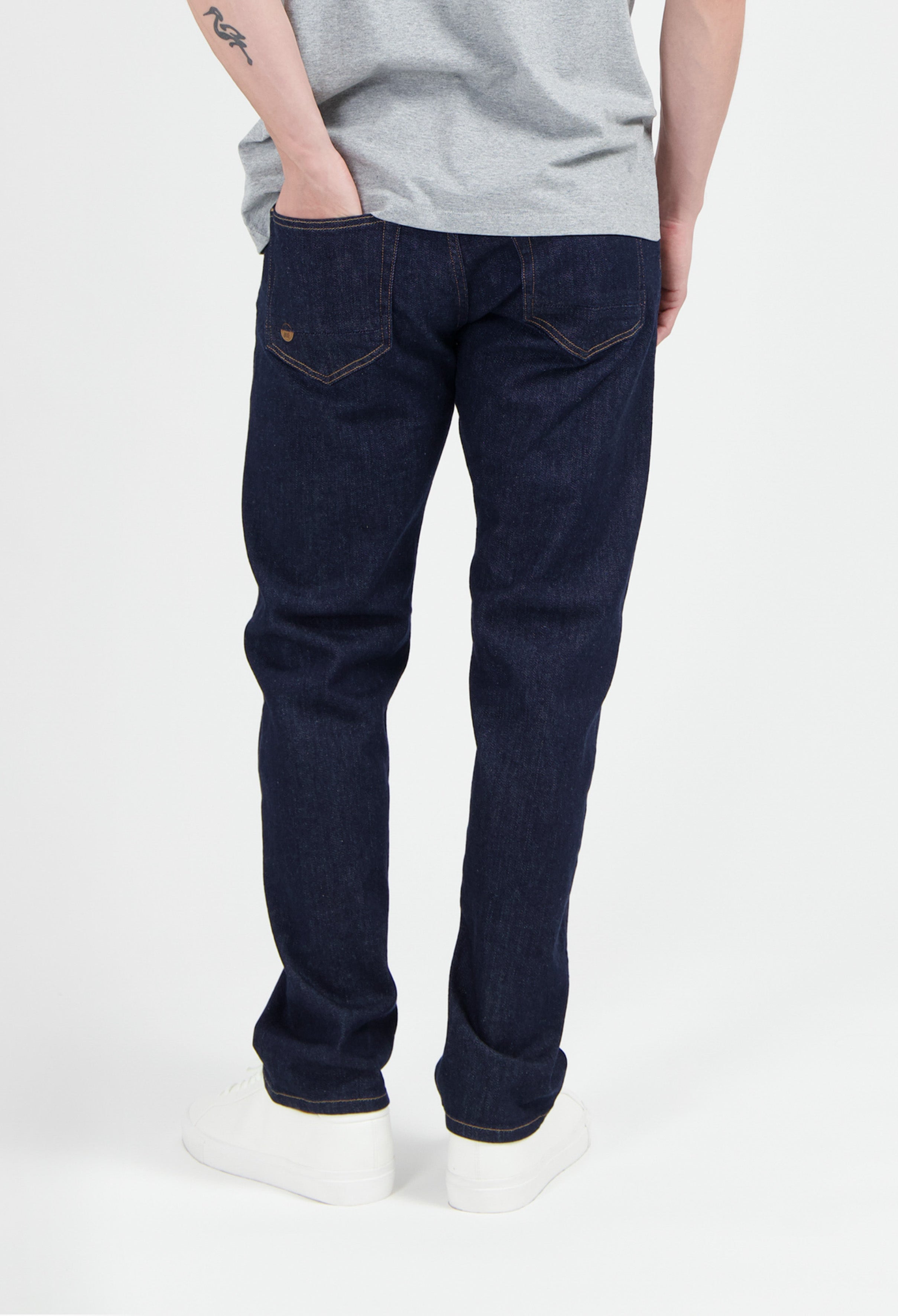 Sustainable MUD Jeans in dark blue denim, classic fit, made from ethical cotton, paired with white sneakers.