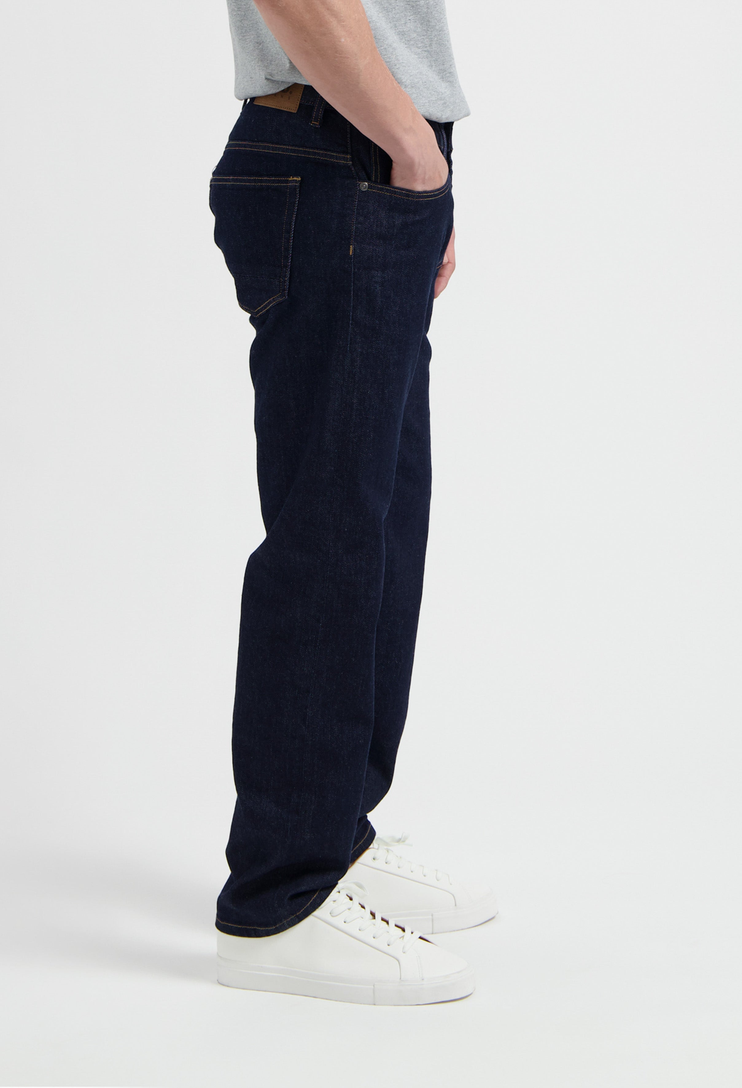 Sustainable MUD Jeans in classic blue denim, worn with a casual gray tee and white sneakers, showcasing ethical style.