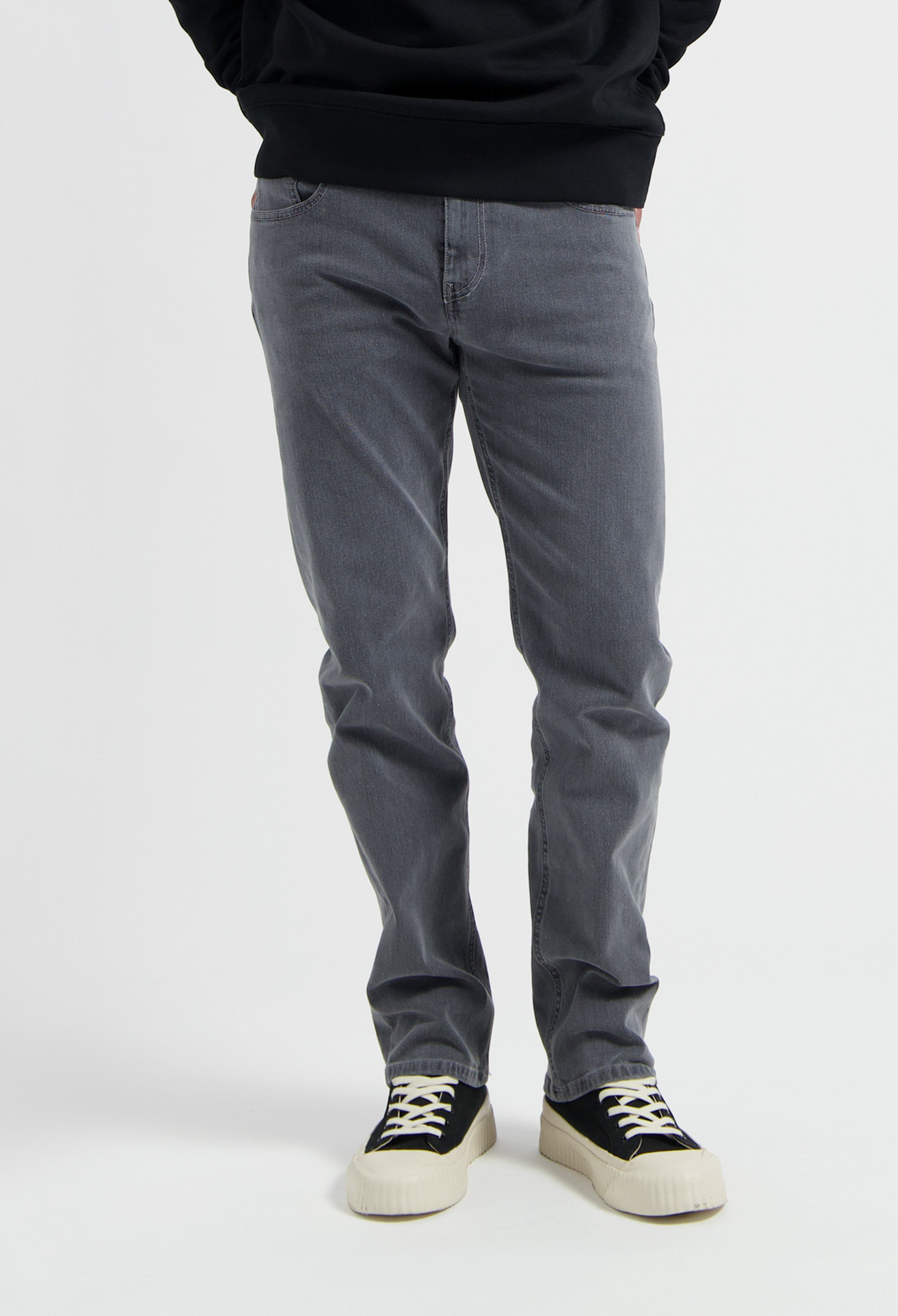 Sustainable MUD Jeans in light blue denim with ethical craftsmanship, paired with a soft gray sweater for casual style.