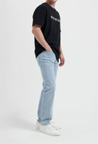 Sustainable MUD Jeans in classic blue denim crafted from organic cotton, paired with a casual white T-shirt.