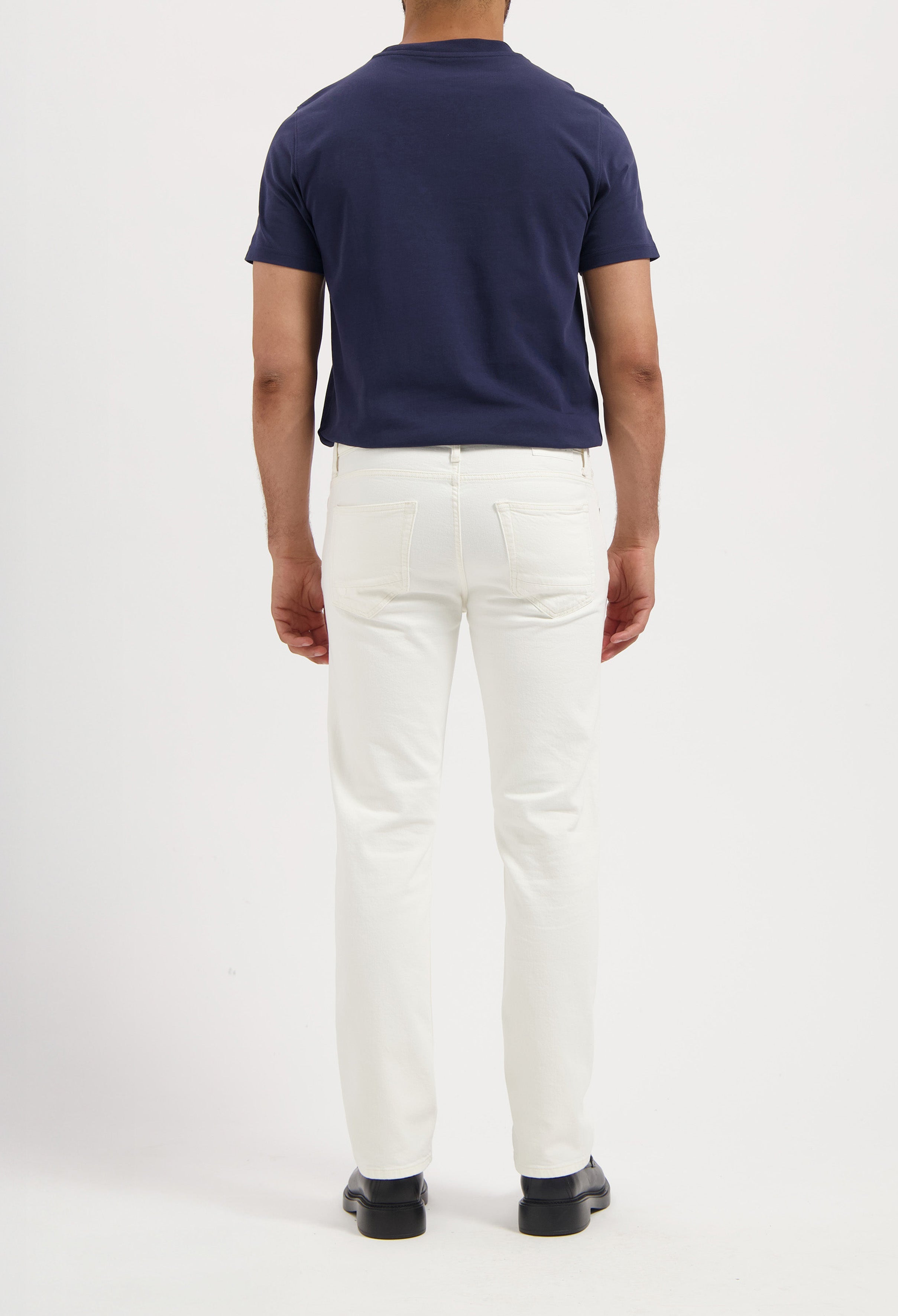 Sustainable MUD Jeans in dark indigo denim, paired with white sneakers, embodying ethical fashion.