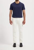 Sustainable MUD Jeans in a slim, white cotton design, paired with a navy t-shirt and black loafers for a classic look.