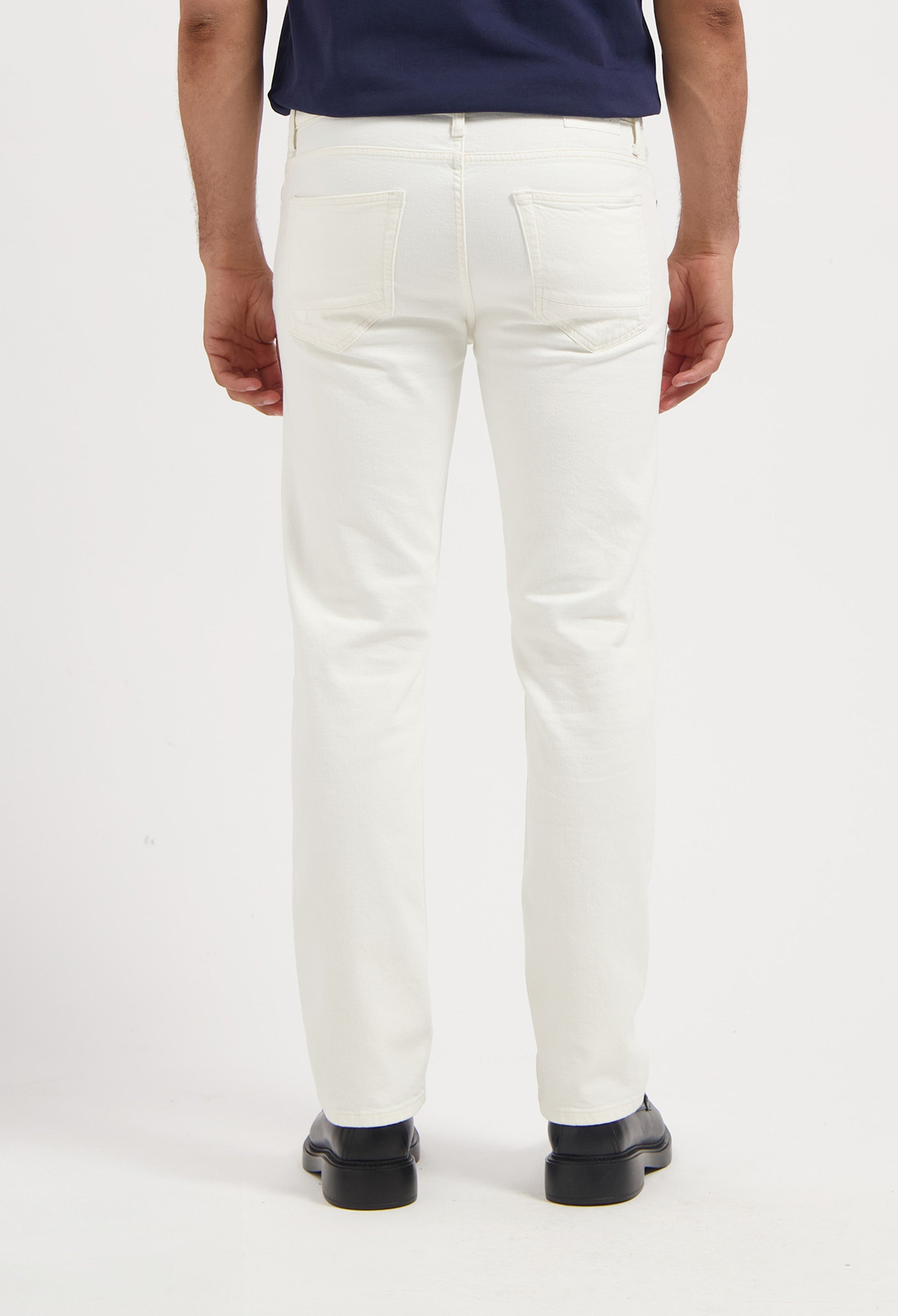 Sustainable MUD Jeans in deep blue denim, relaxed fit, worn with a black t-shirt and white sneakers for an ethical style.