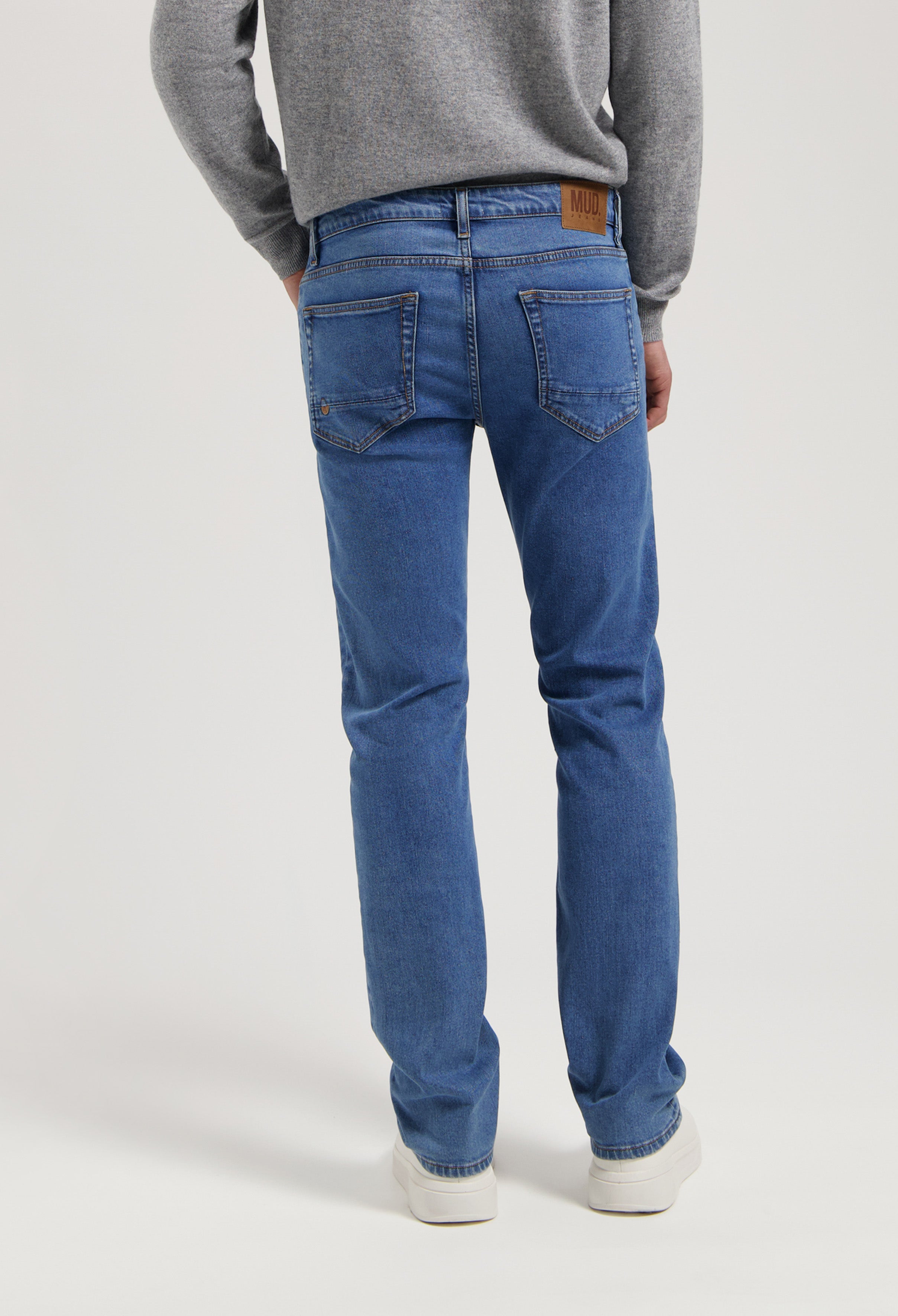 Sustainable MUD Jeans made from eco-friendly materials, featuring classic blue denim in a straight fit, paired with a gray sweater.