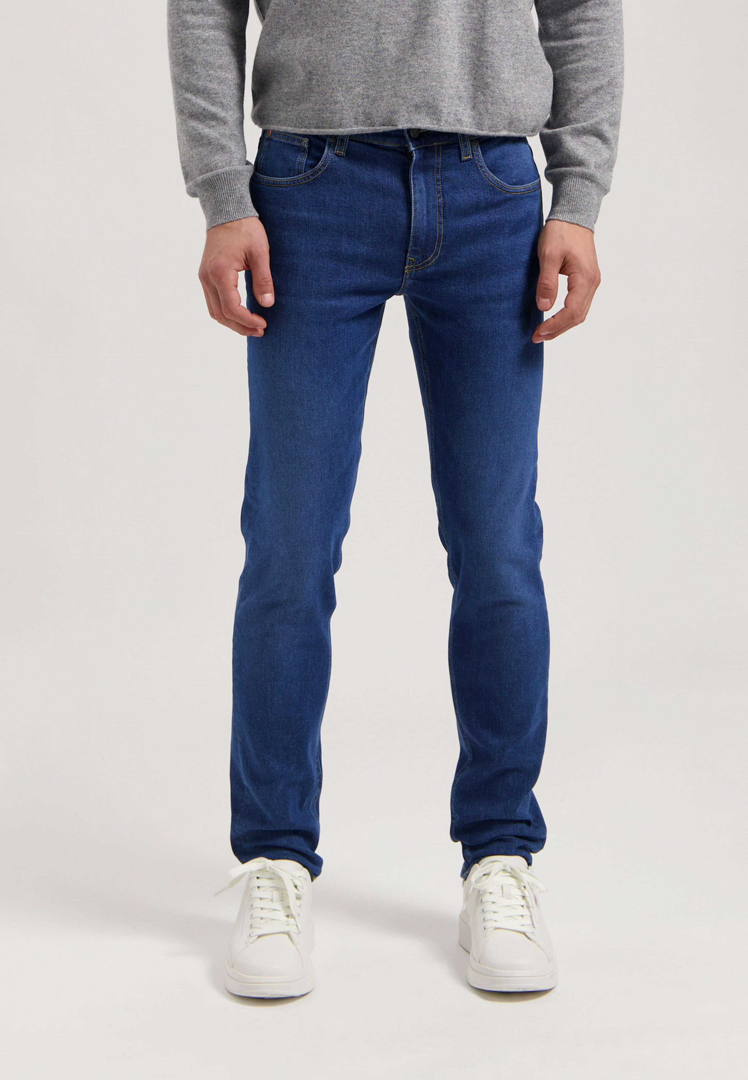 Sustainable MUD Jeans set in deep blue denim, featuring a classic jacket and jeans, paired with a light gray shirt.
