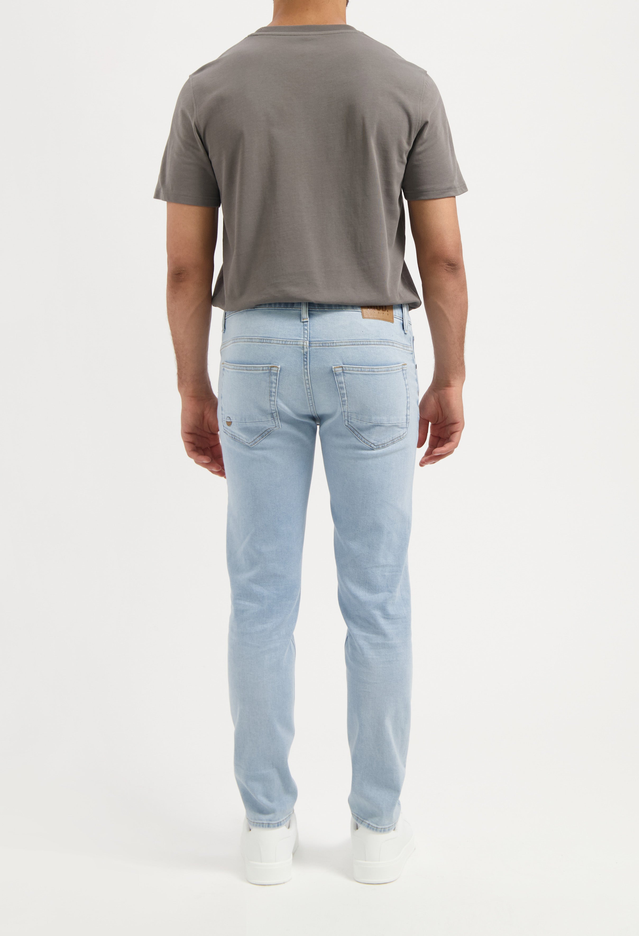 Sustainable MUD Jeans in light blue denim, crafted from organic cotton, worn with a pale green top, ethical fashion.