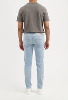 Sustainable MUD Jeans in light blue denim, crafted from organic cotton, worn with a pale green top, ethical fashion.