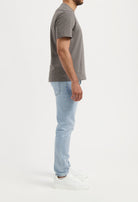 Sustainable MUD Jeans in beige, crafted from organic cotton, styled with a gray t-shirt and white sneakers.