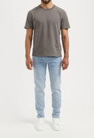 Sustainable MUD Jeans shorts in light blue denim, made from organic cotton, paired with a white T-shirt and sneakers.