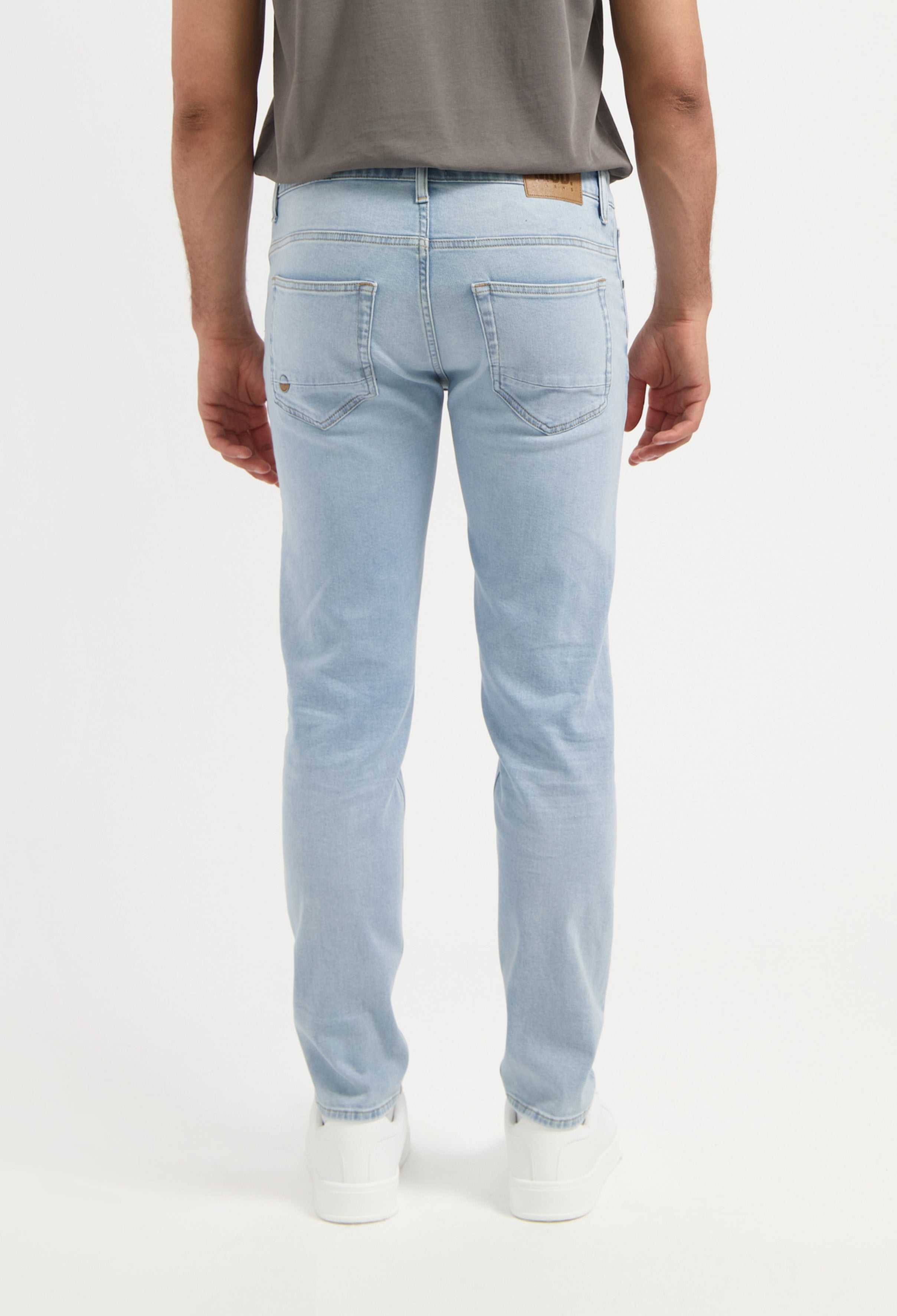 Sustainable MUD Jeans beige shorts made from eco-friendly materials, worn with gray shirt and white sneakers.