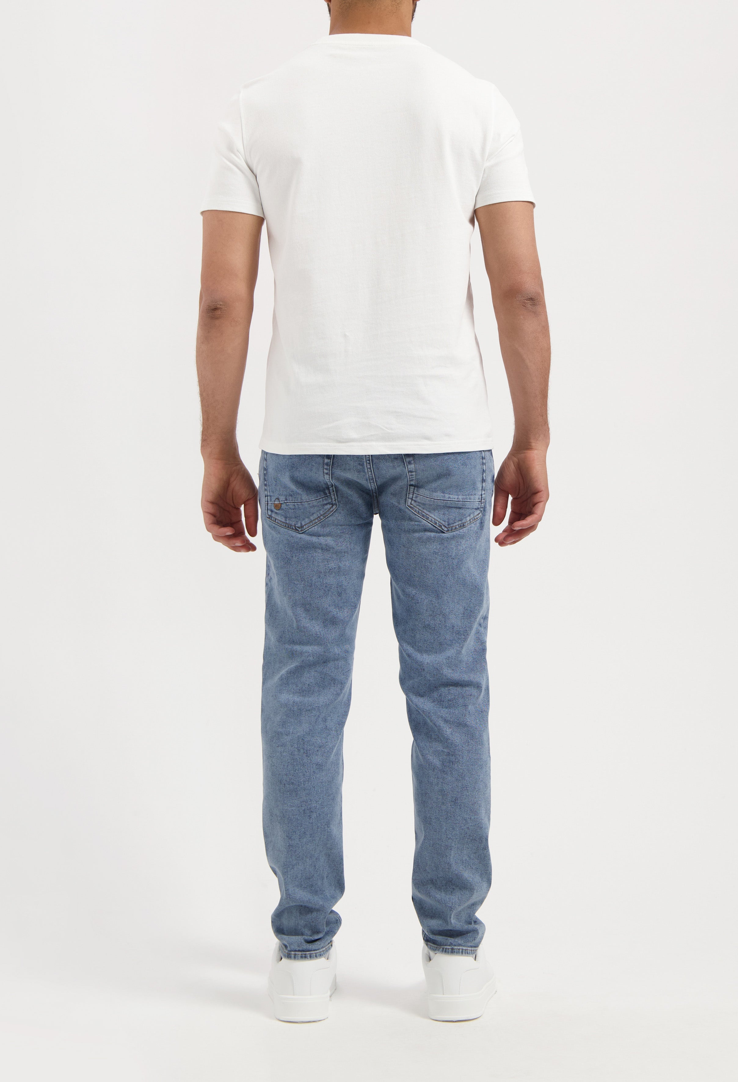 Sustainable MUD Jeans crafted from organic cotton in a modern blue short design, paired with a black tee and white sneakers.
